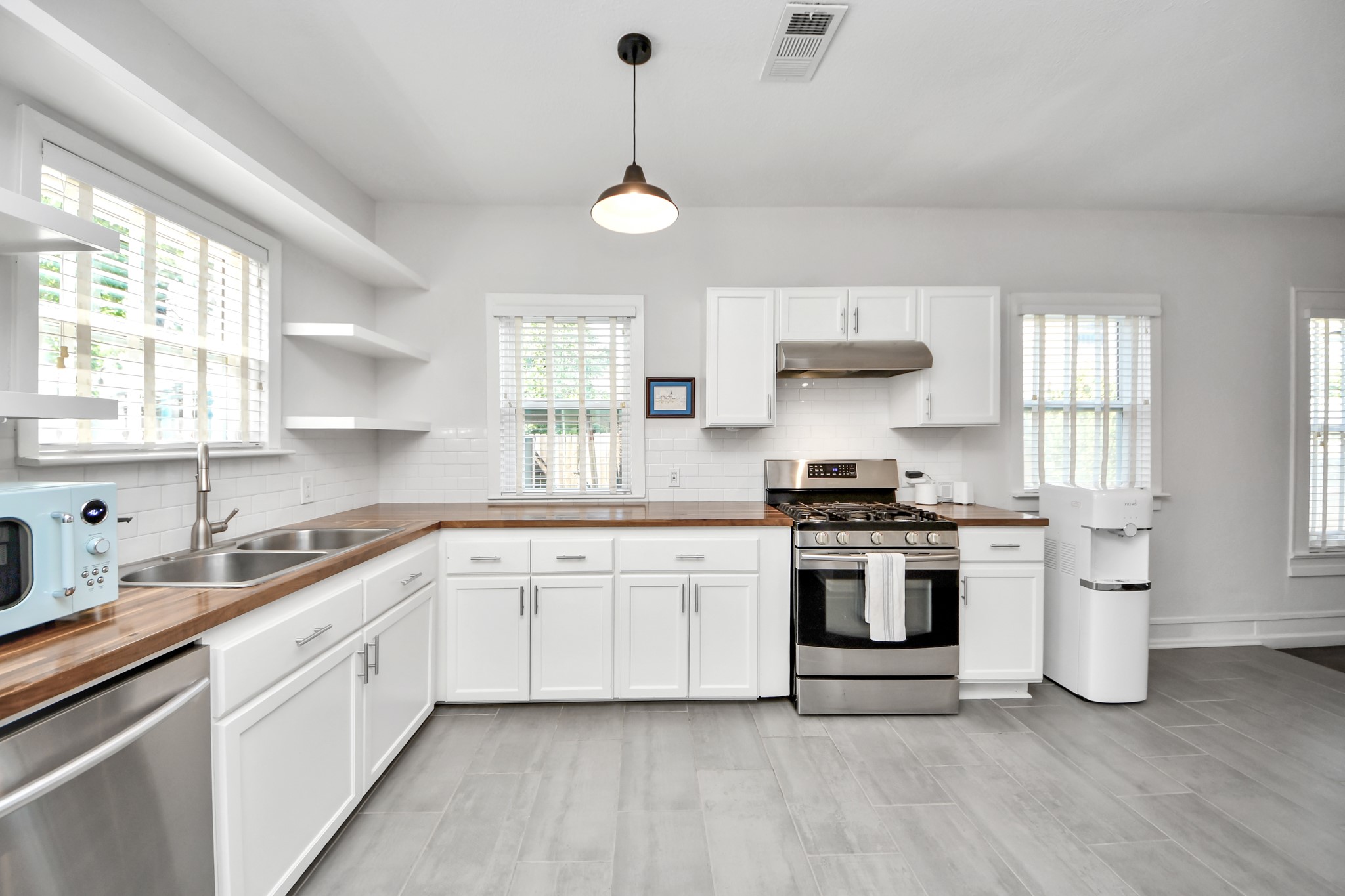 Warm walnut butcher block countertops complement the classic subway tile backsplash, creating a kitchen that feels both timeless and welcoming.