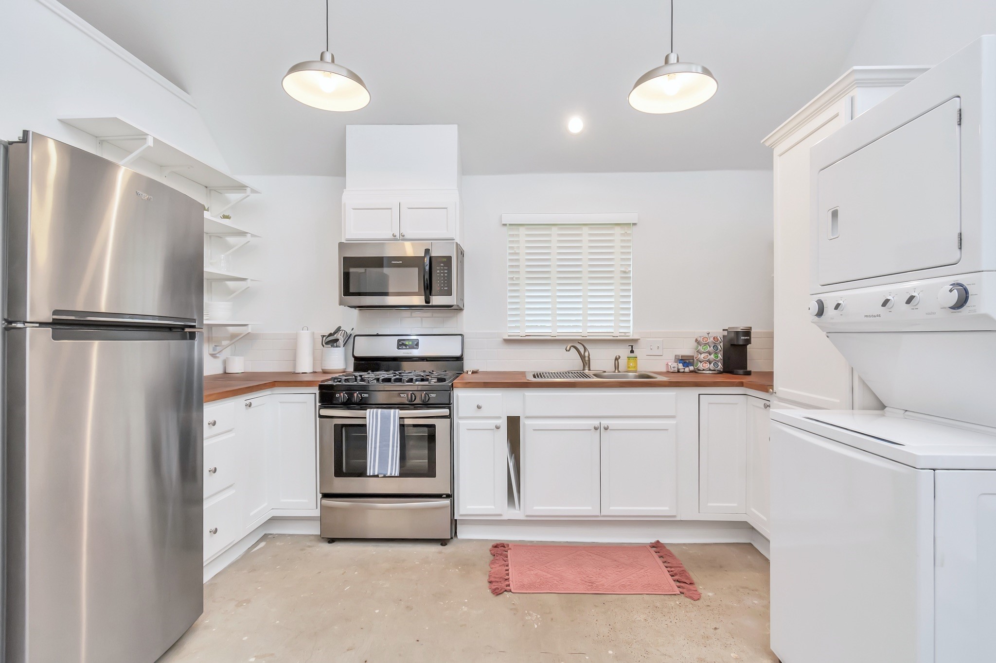 A spacious and thoughtfully designed kitchen featuring stainless steel appliances, walnut butcher block countertops, and timeless subway tile backsplash.