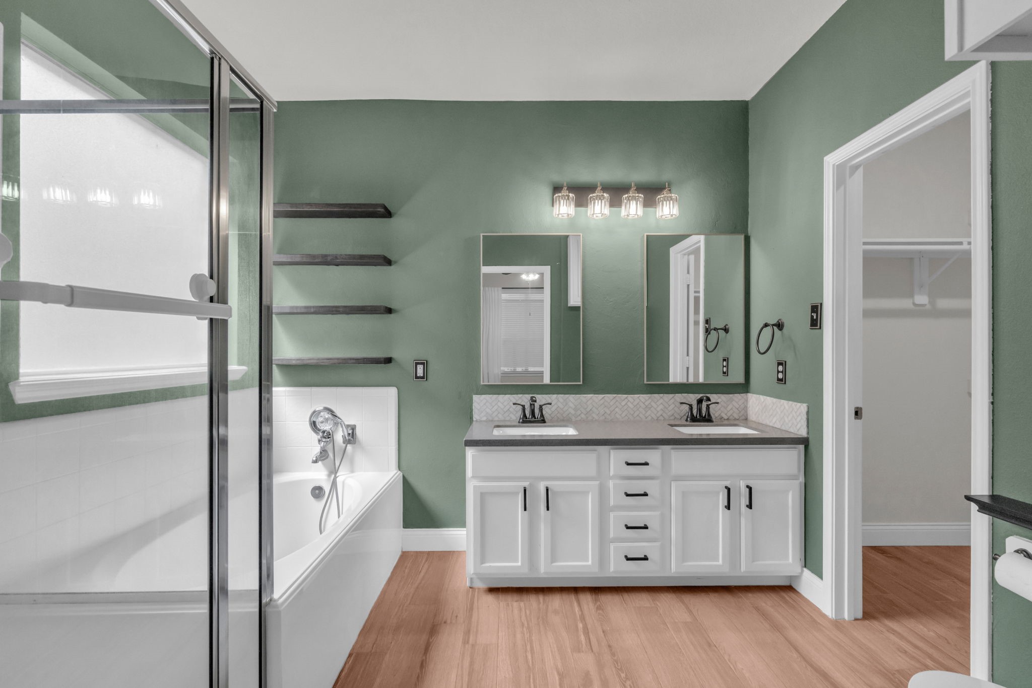 Stunning primary bathroom features dual vanities, a soaking tub, a glass-standing shower, and a massive walk-in closet.