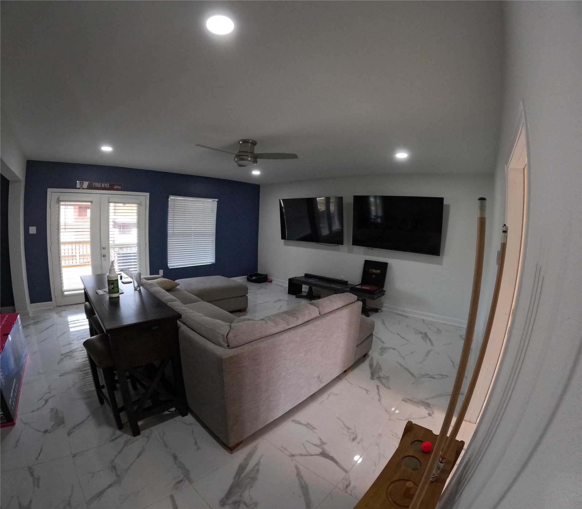 Living space on the second floor with white marble floors and twin flatscreens for entertaining