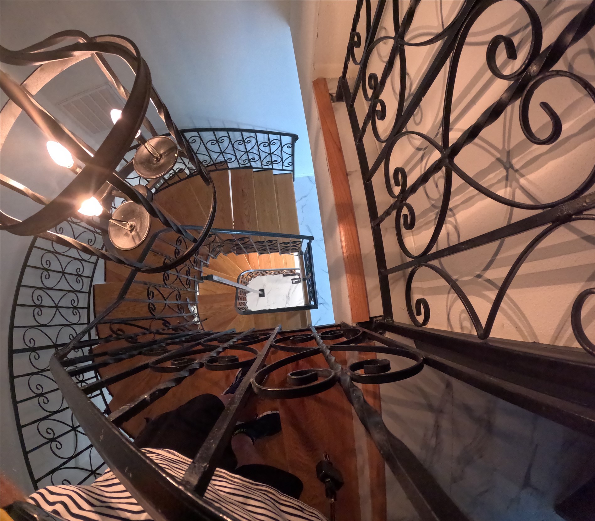Looking down the curved wroght irn staircase that goes from top to bottom. The home has room for an elevator to be installed.