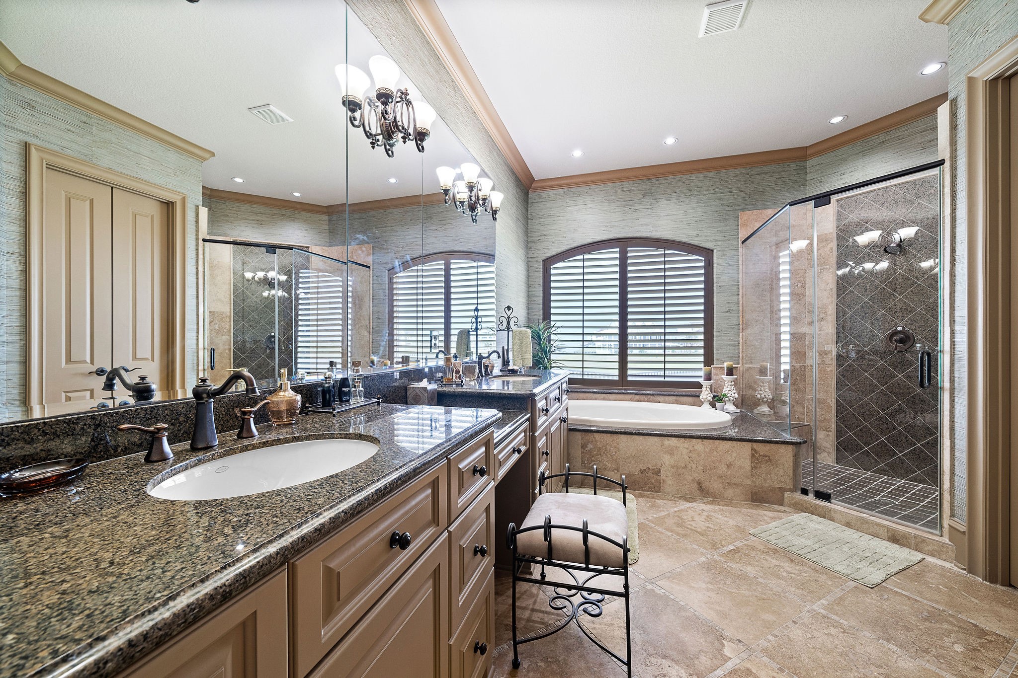 The primary bath features dual sinks, vanity area, custom finishes throughout, a luxurious walk-in shower, and a soaking tub