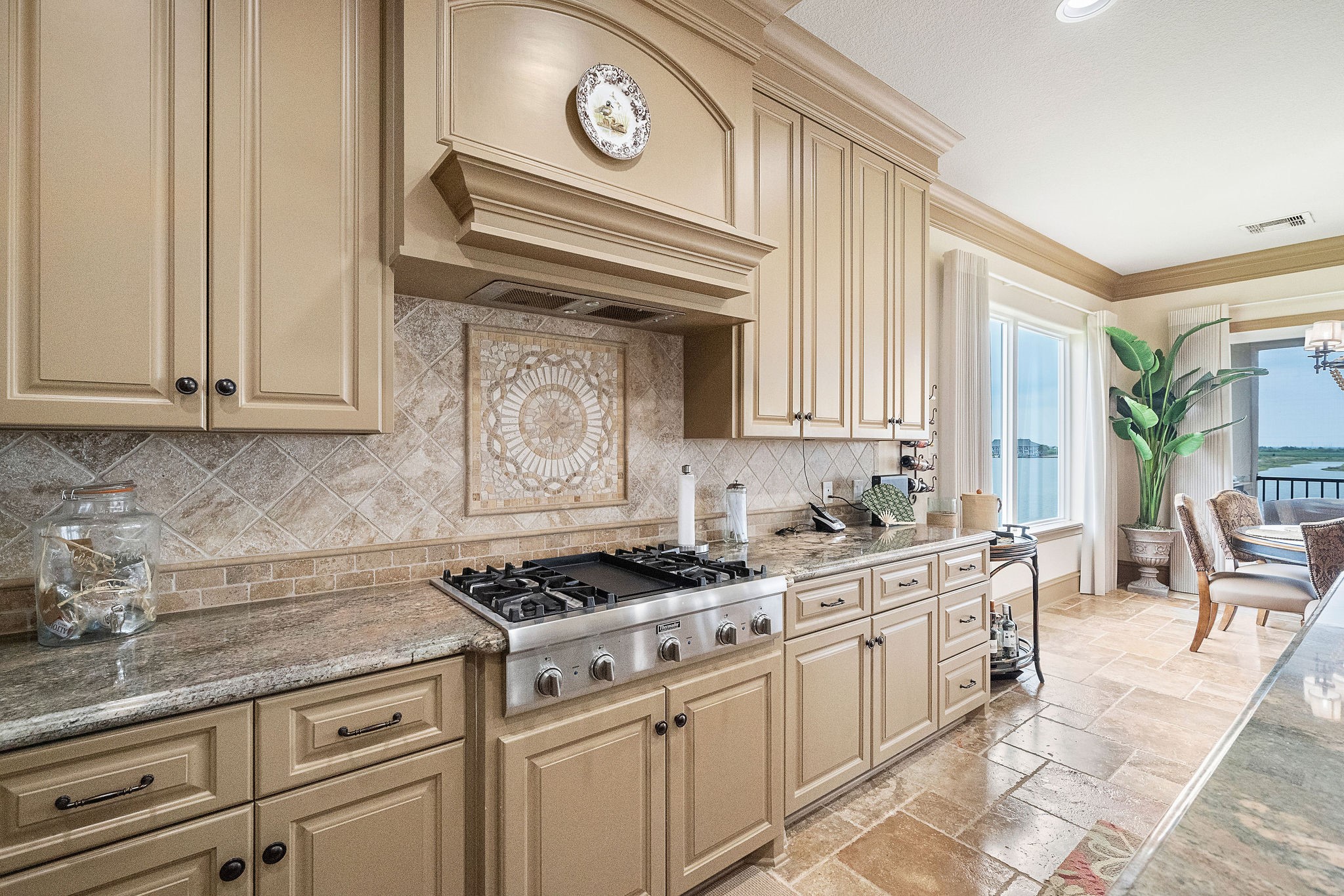 The gourmet kitchen showcases a gas cooktop, granite counters, and a mosaic backsplash