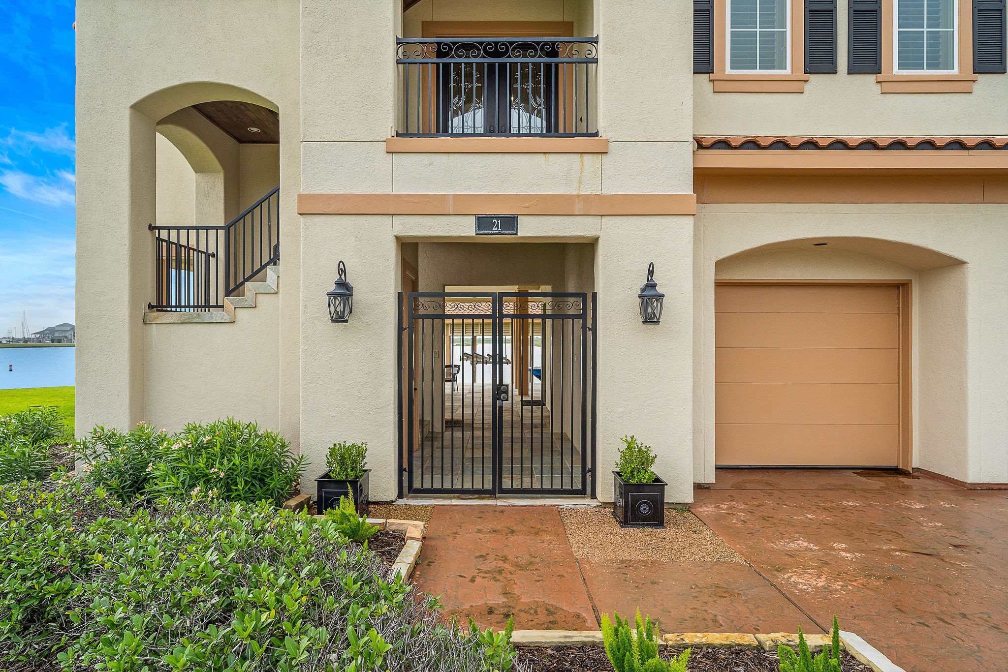 This waterfront home offers a ground-level entry framed by lush landscaping. Pass through the wrought-iron gates  to the left, leading to the entry stairway, or continue straight to the dockside living area on the ground level