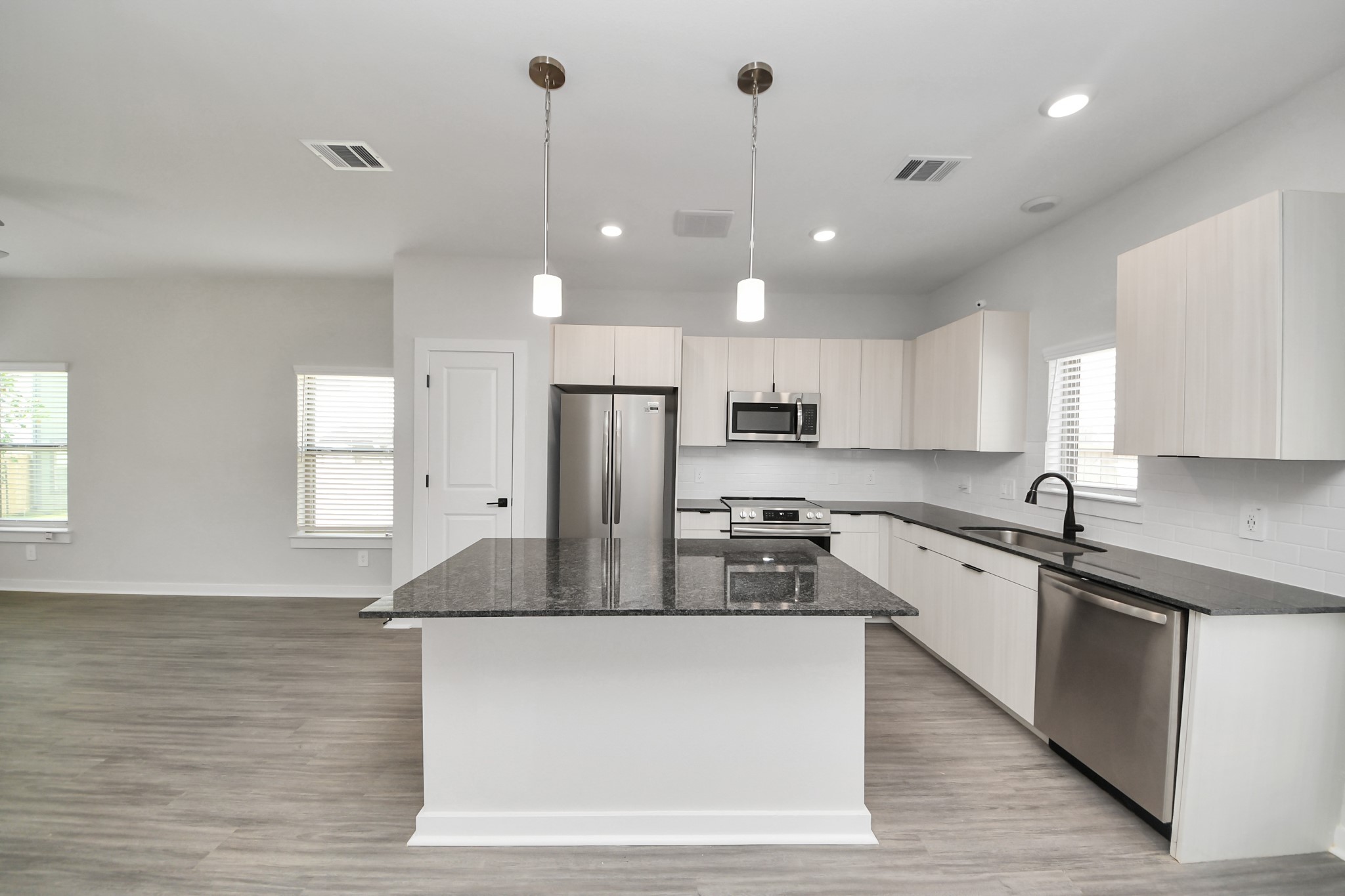 Boasting luxury finishes-stylish Island kitchen,granite counters,subway tile backsplash,ample custom cabinet space,stainless appliances,refrigerator,full size washer&dryer included,wood-like flooring throughout,open concept floor plan.