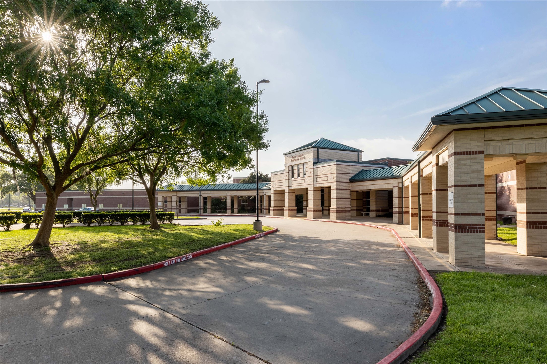 Beautiful community entrance surrounded by mature trees and manicured landscaping.