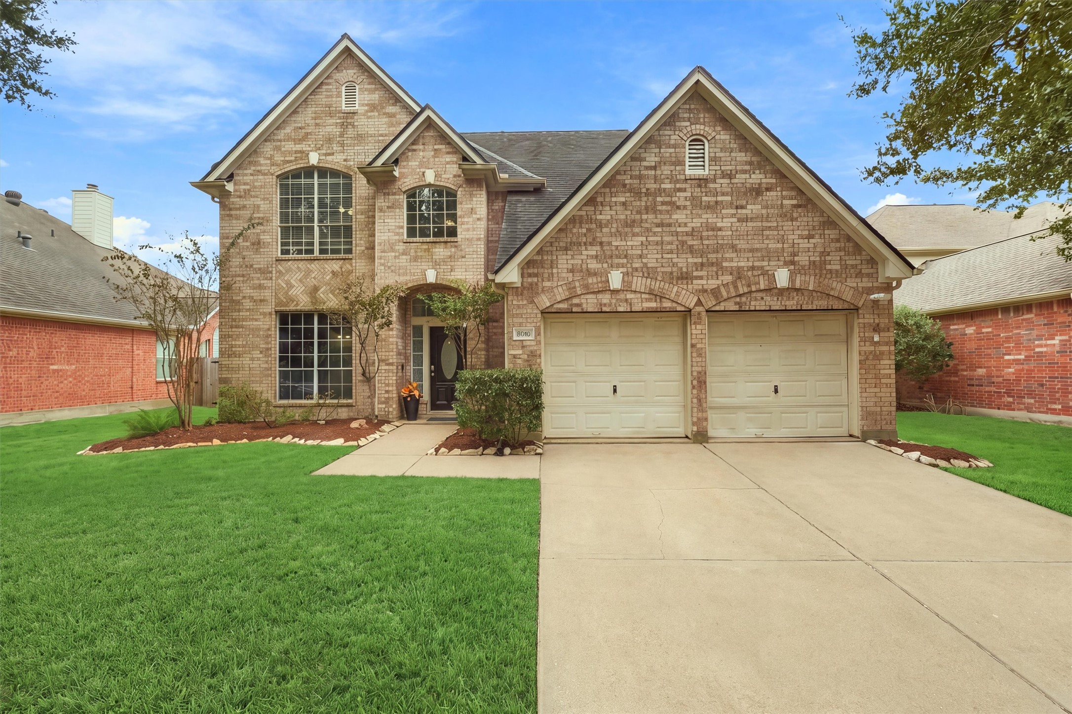 Beautiful front elevation surrounded by mature landscaping and a manicured lawn.