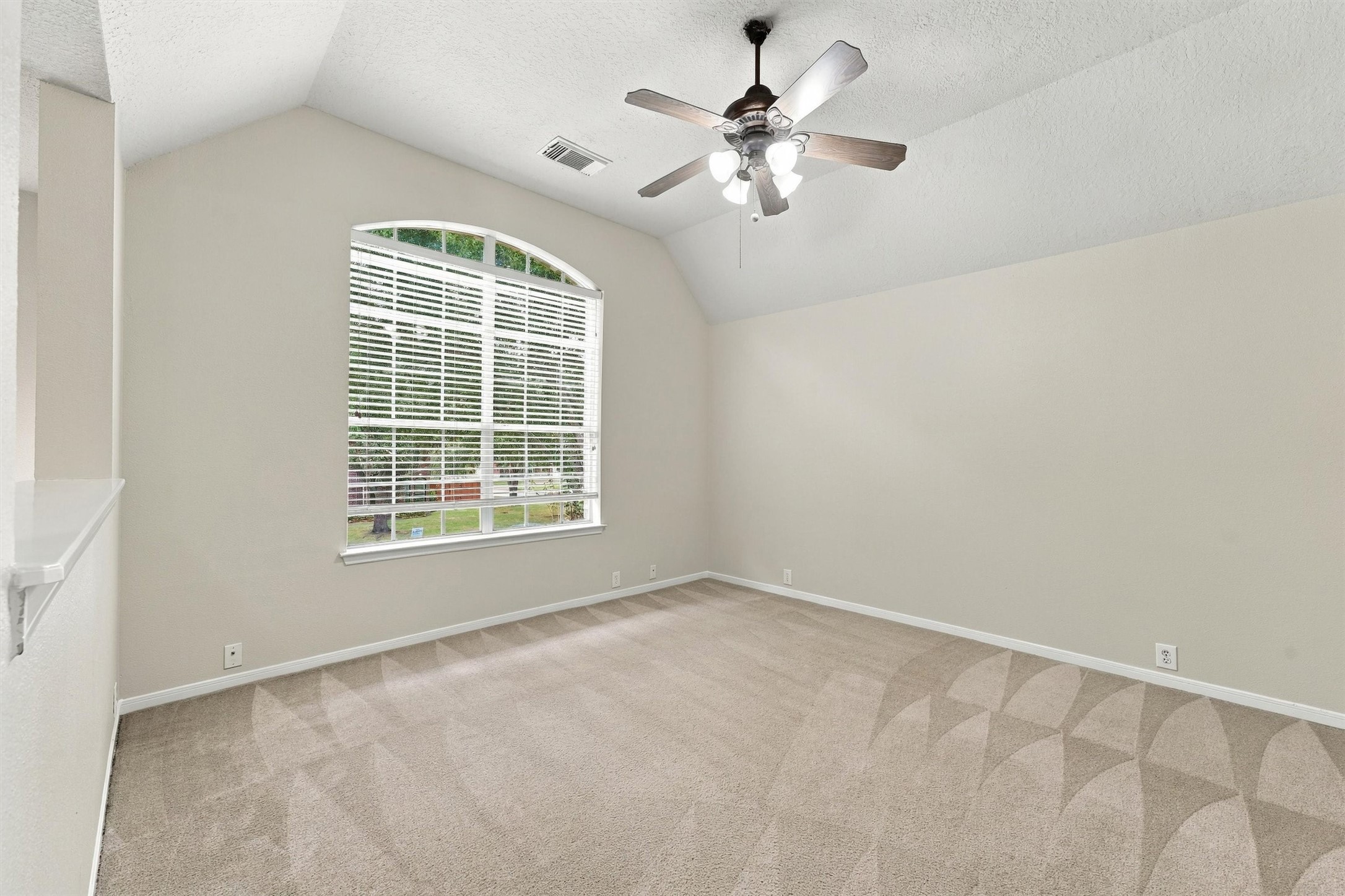 Spacious secondary bedroom featuring a large window, ceiling fan, and neutral finishes.