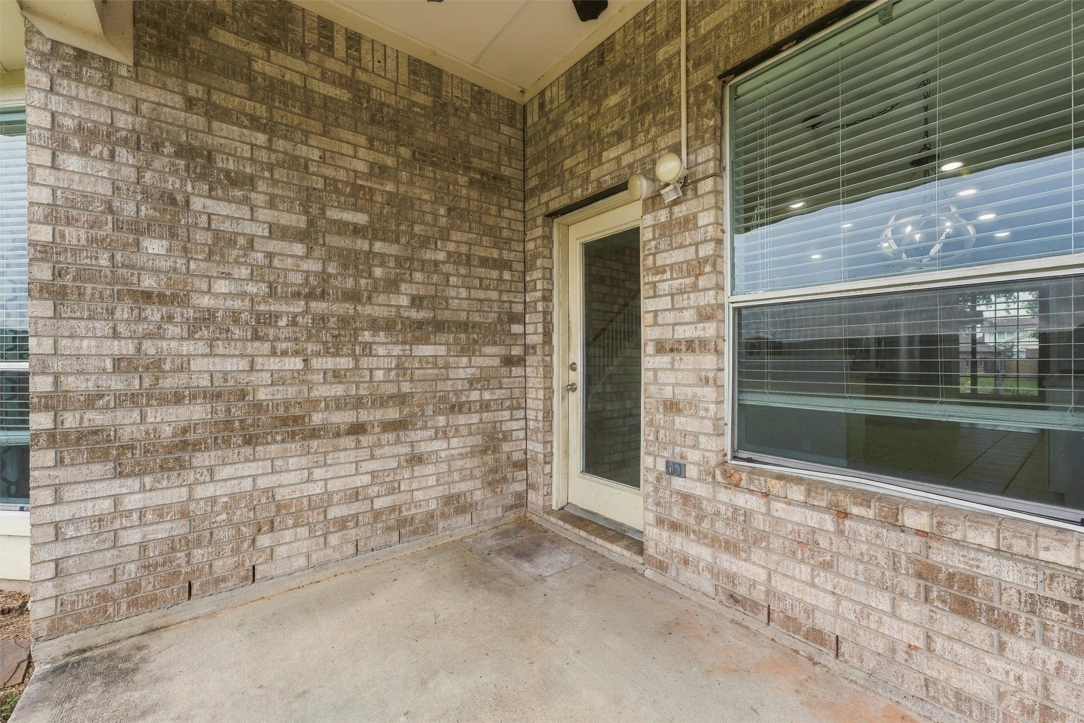 Another view of the covered patio featuring a brick exterior and backyard access.