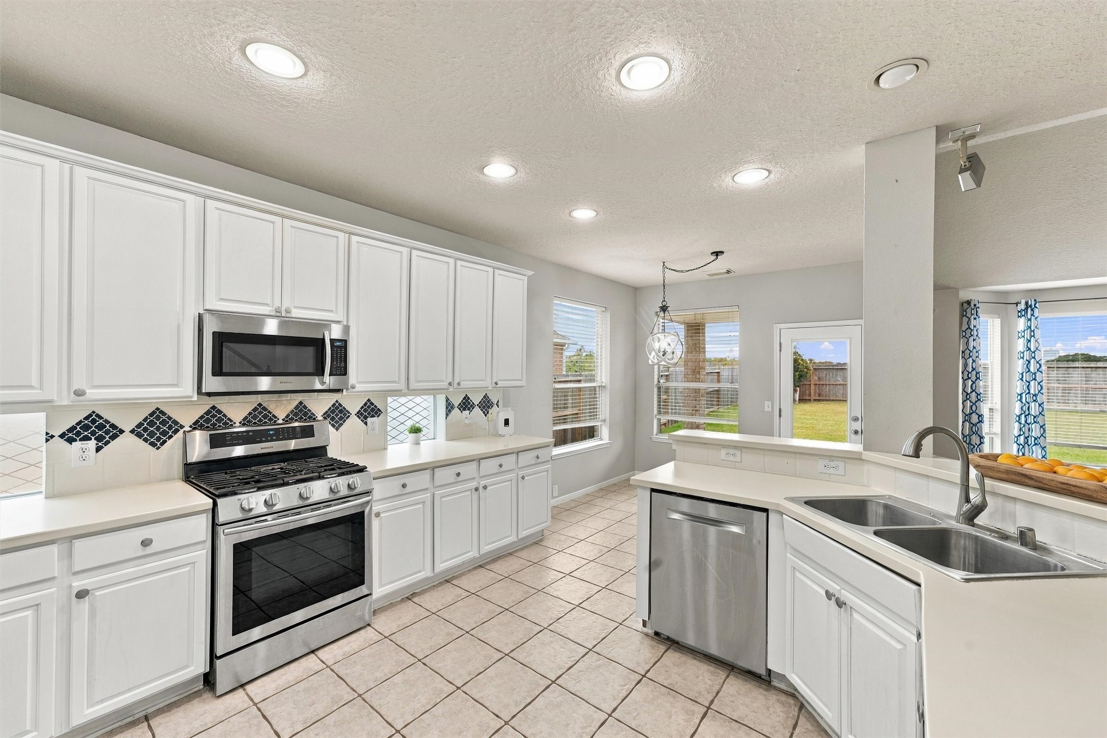 Bright and inviting kitchen featuring white cabinetry, stainless steel appliances, and generous counter space.