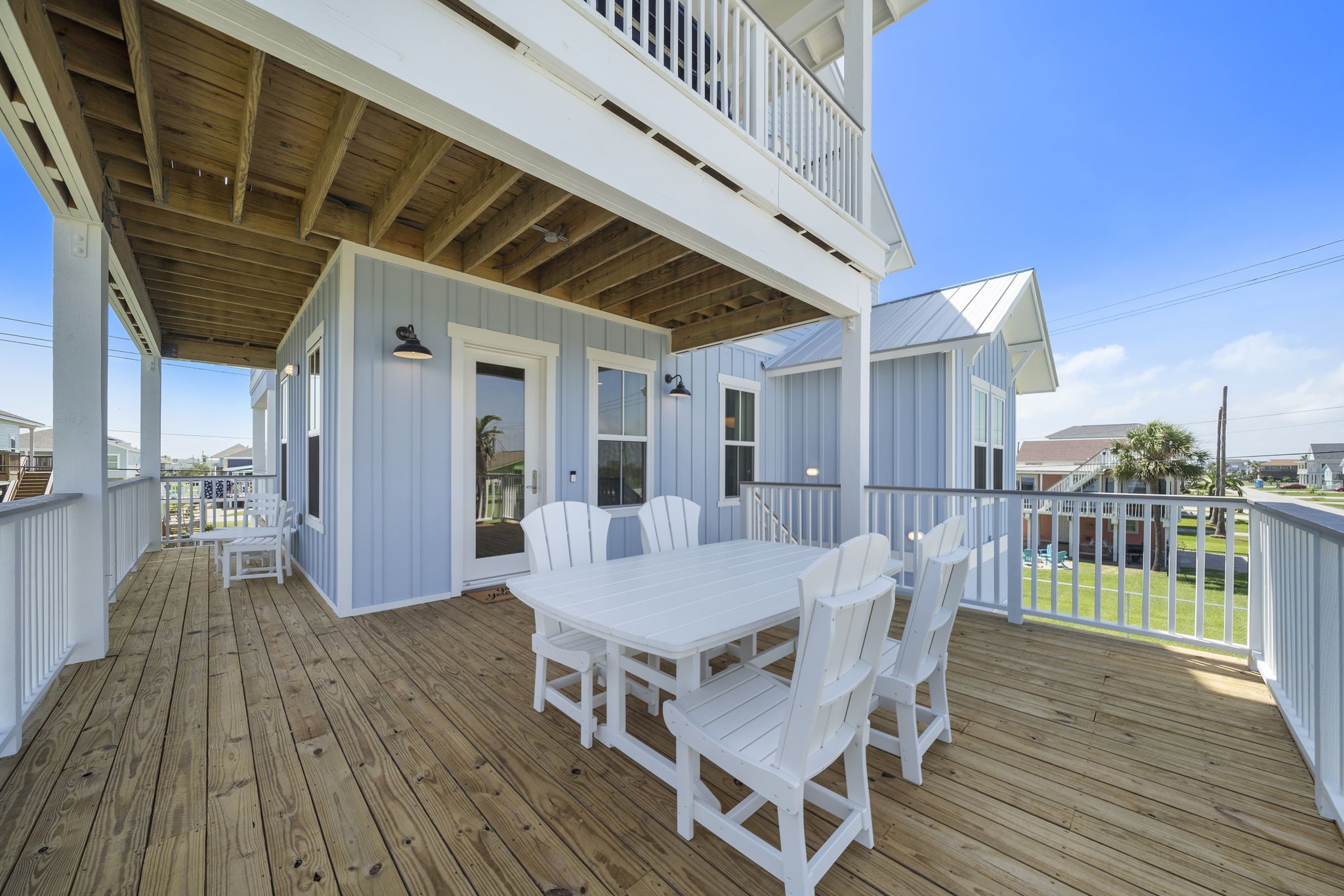 Spacious wooden deck perfect for outdoor dining, featuring a charming table set and coastal views.
