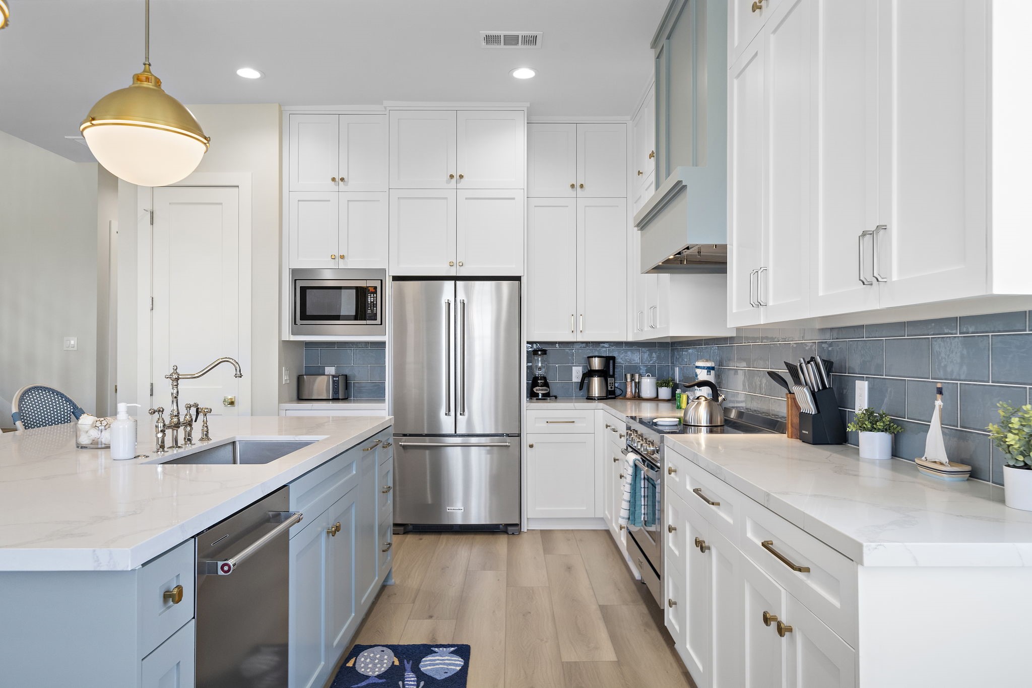 Bright and modern kitchen featuring sleek white cabinetry, stainless steel appliances, and a stylish blue tile backsplash.