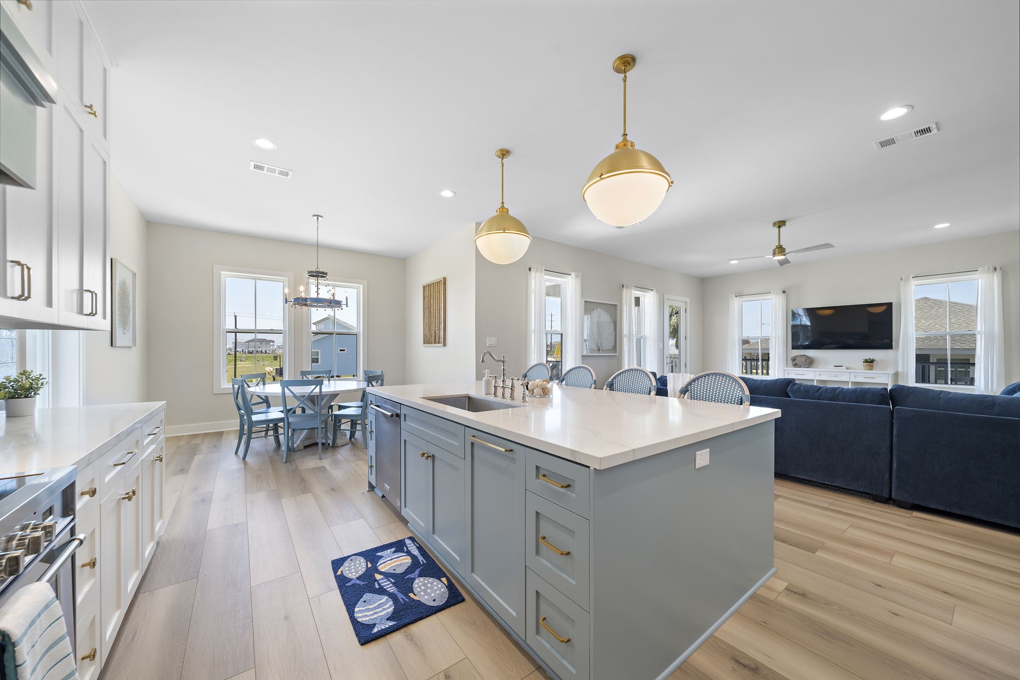 Spacious and bright open-concept living area featuring a modern kitchen with a large island, elegant pendant lighting, and sleek cabinetry, seamlessly flowing into a cozy dining and living space. Spacious and bright open-concept living area featuring a modern kitchen with a large island, elegant pendant lighting, and sleek cabinetry, seamlessly flowing into a cozy dining and living space.