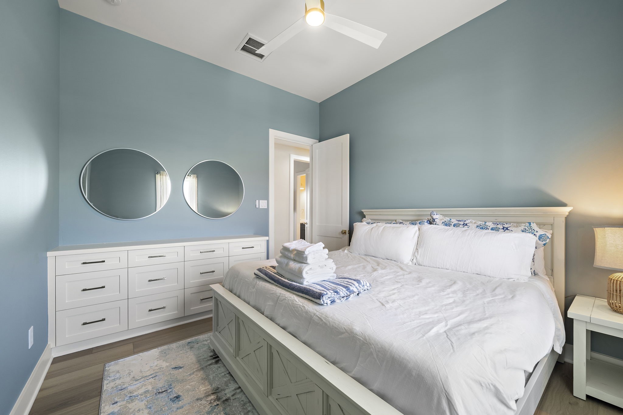 Charming bedroom with soothing blue walls, elegant white furniture, and modern decor, creating a serene and inviting atmosphere.