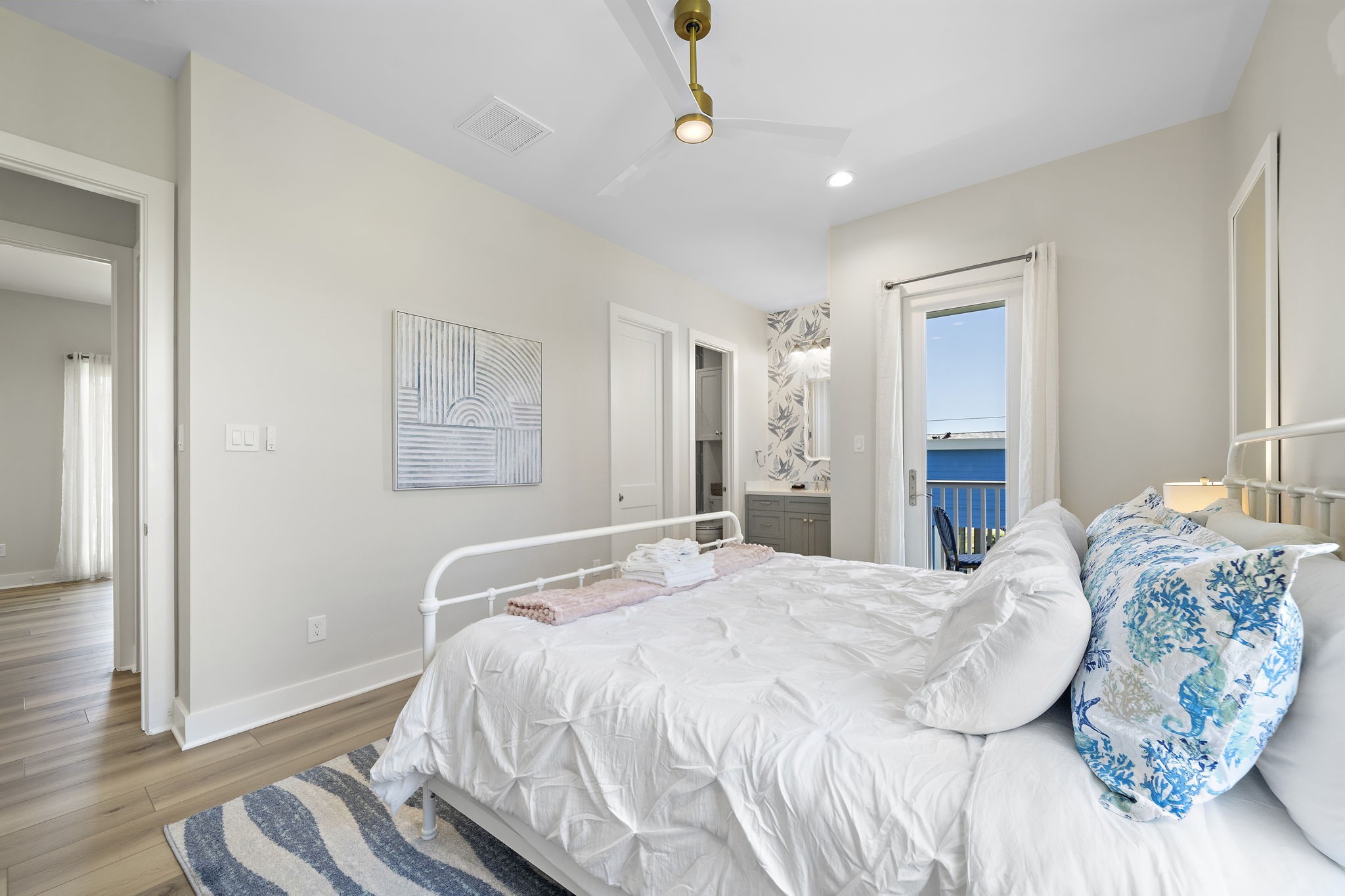 Bright and inviting bedroom featuring a cozy bed, stylish decor, and a private balcony access with serene views.