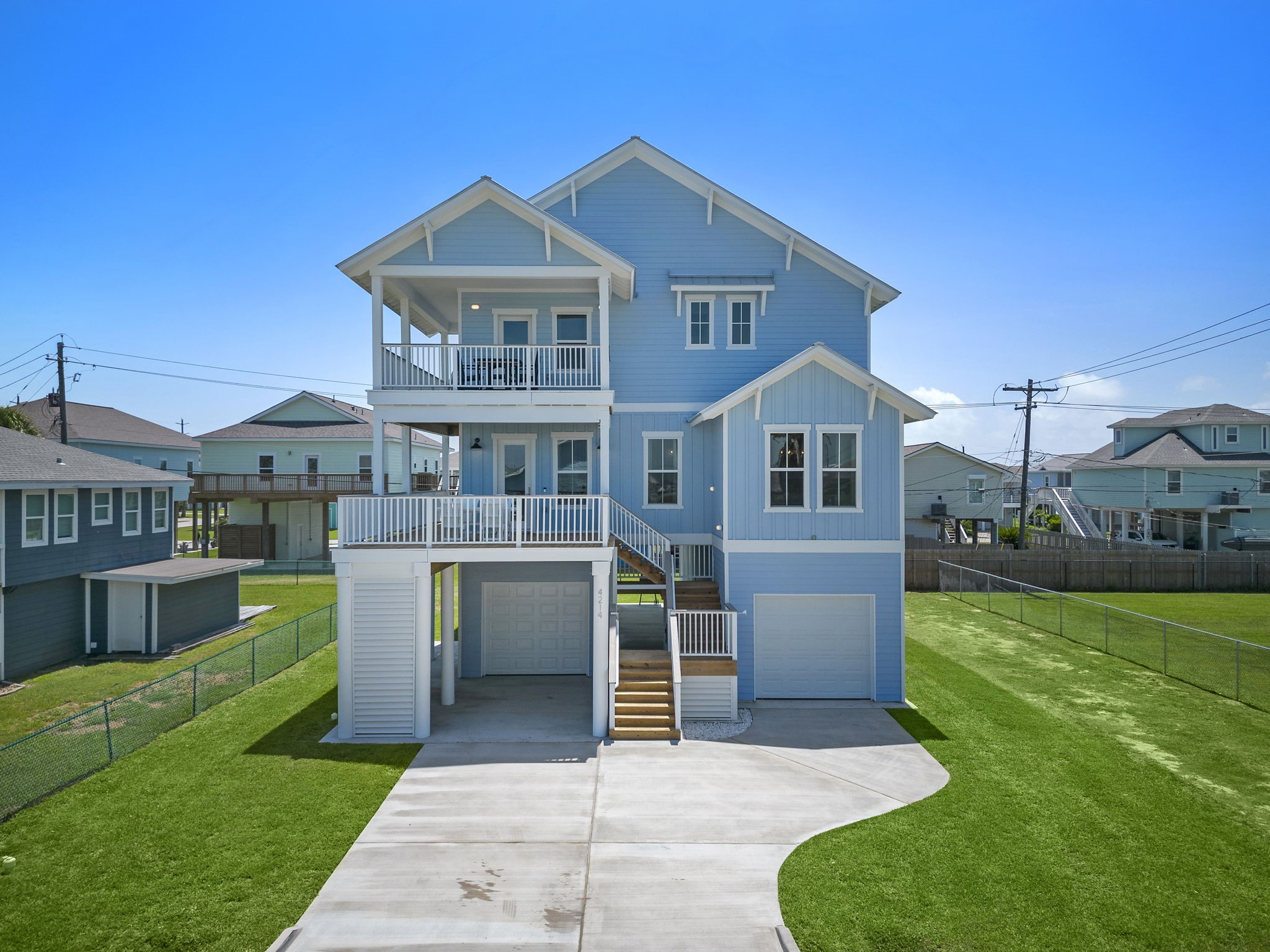 Charming coastal home with a fresh blue exterior, spacious balconies, and elevated design offering stunning views. Enjoy a generous driveway and neatly landscaped yard, perfect for coastal living. Charming coastal home with a fresh blue exterior, spacious balconies, and elevated design offering stunning views. Enjoy a generous driveway and neatly landscaped yard, perfect for coastal living.