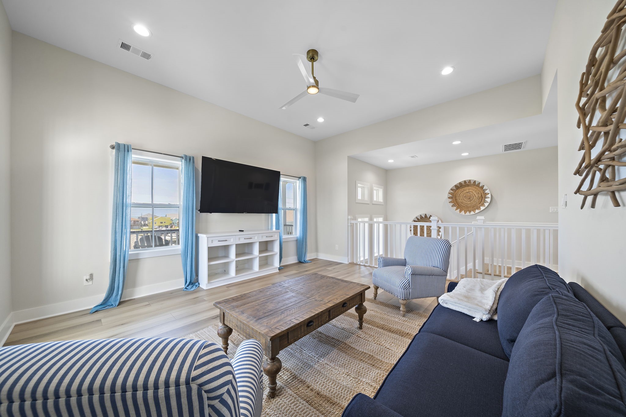 Bright and airy living space featuring large windows with coastal views, a ceiling fan, and comfortable seating, perfect for relaxation and entertainment. Bright and airy living space featuring large windows with coastal views, a ceiling fan, and comfortable seating, perfect for relaxation and entertainment.