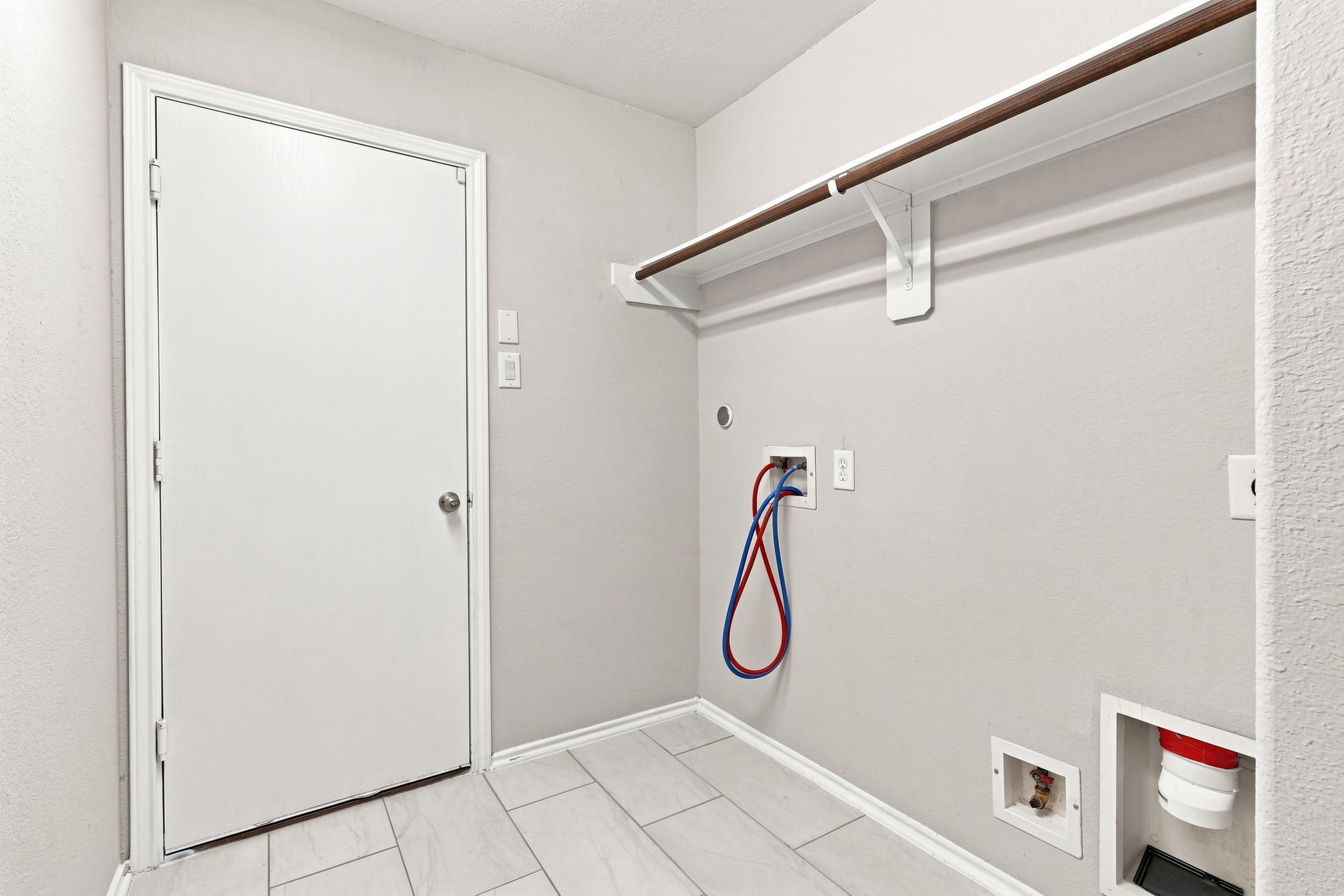 Interior utility room with washer and dryer connections and built-in hanging/storage space.