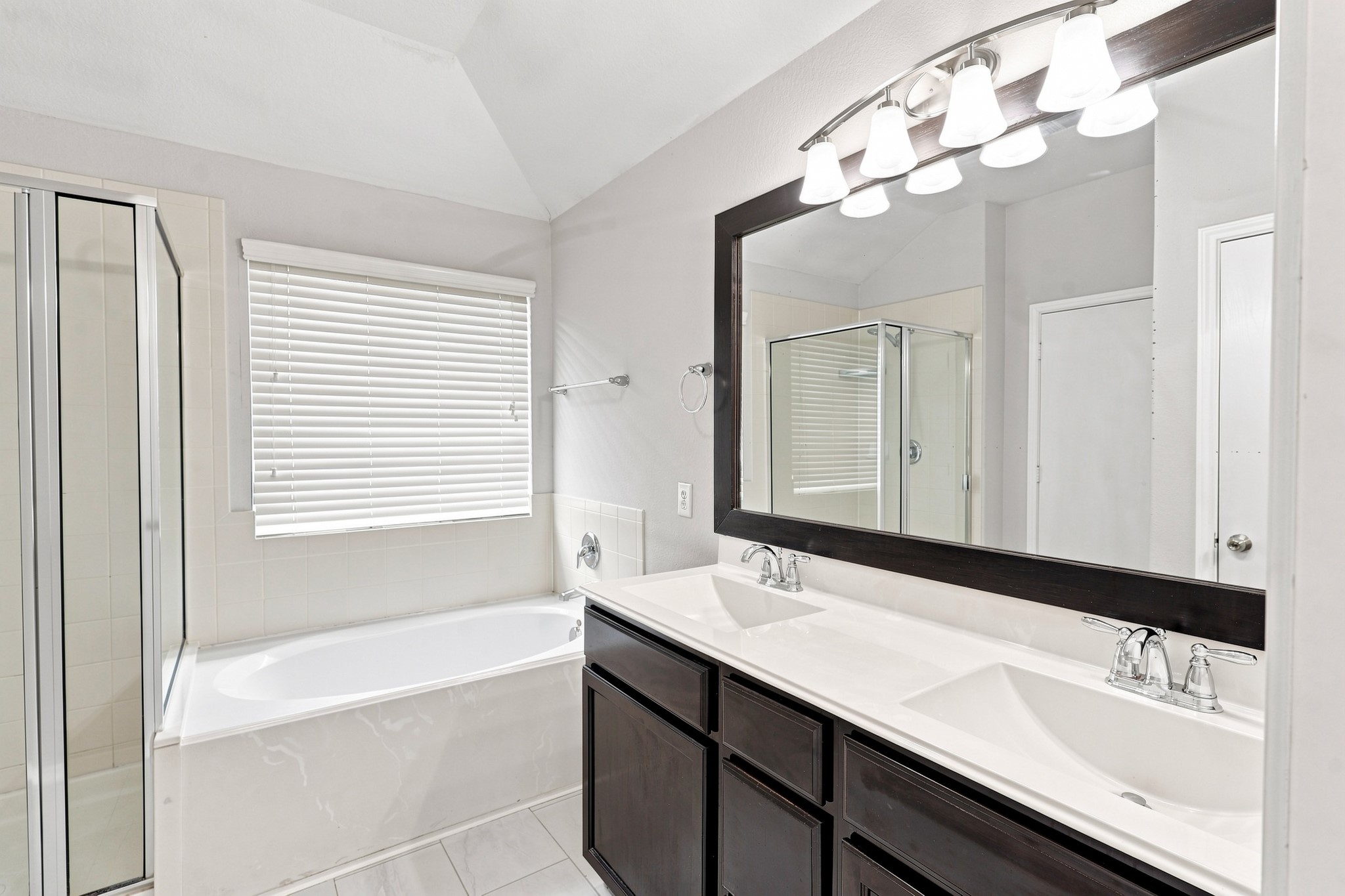 Primary bathroom with dual sinks, large vanity, soaking tub, separate shower, and oversized mirror.