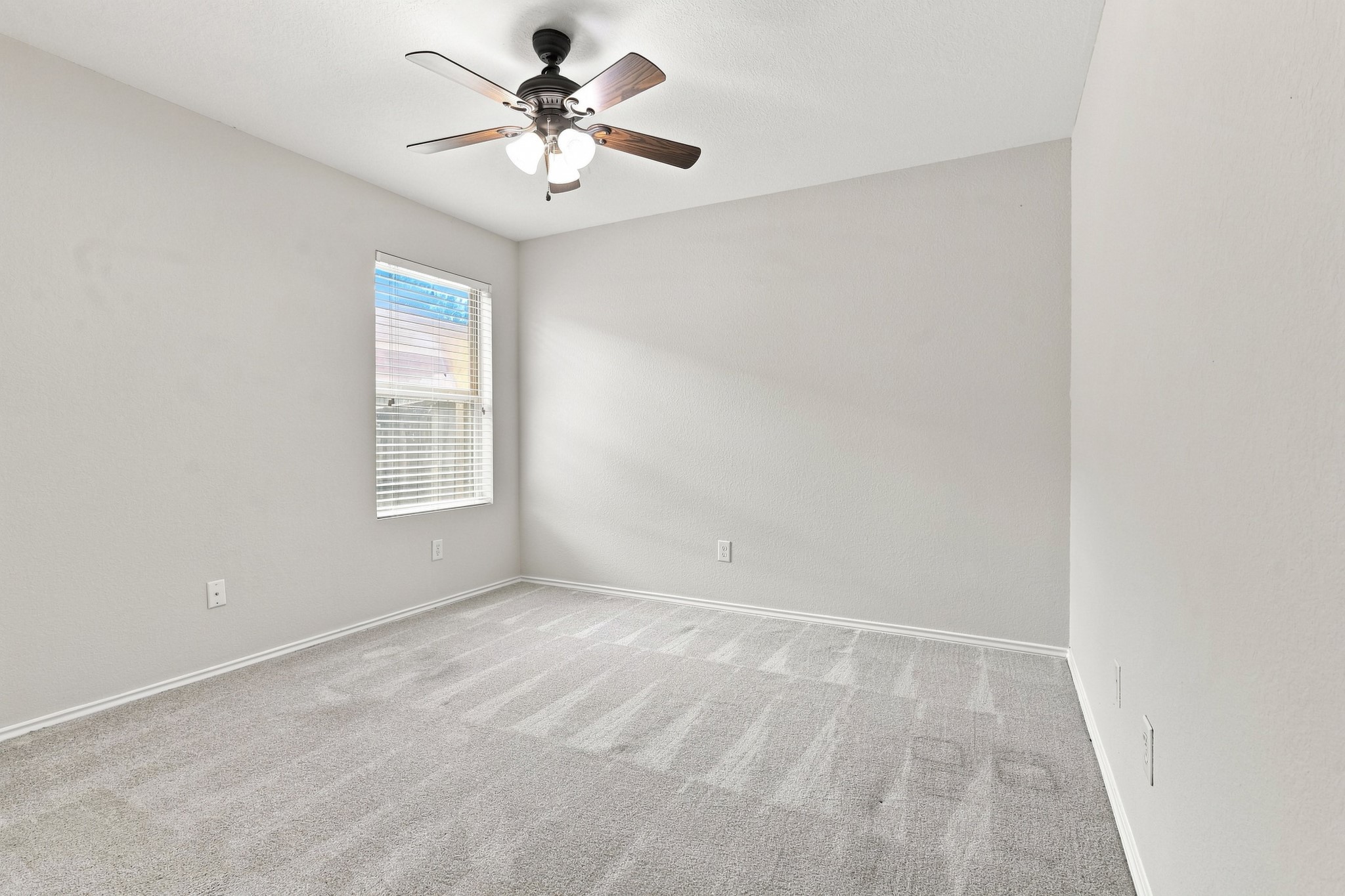 Third bedroom with neutral carpet, ceiling fan, and natural light.