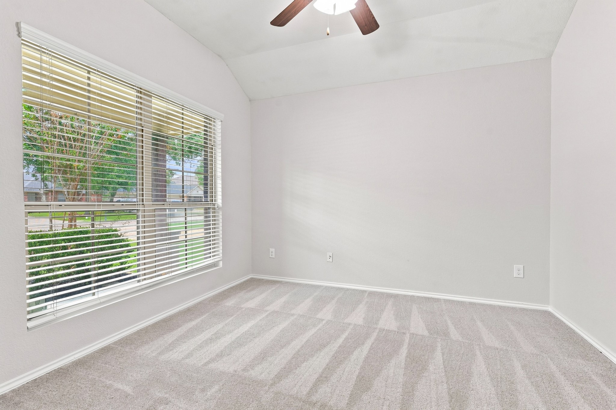 Dedicated study/home office with vaulted ceiling, ceiling fan, large window, and neutral carpet. Dedicated study/home office with vaulted ceiling, ceiling fan, large window, and neutral carpet.