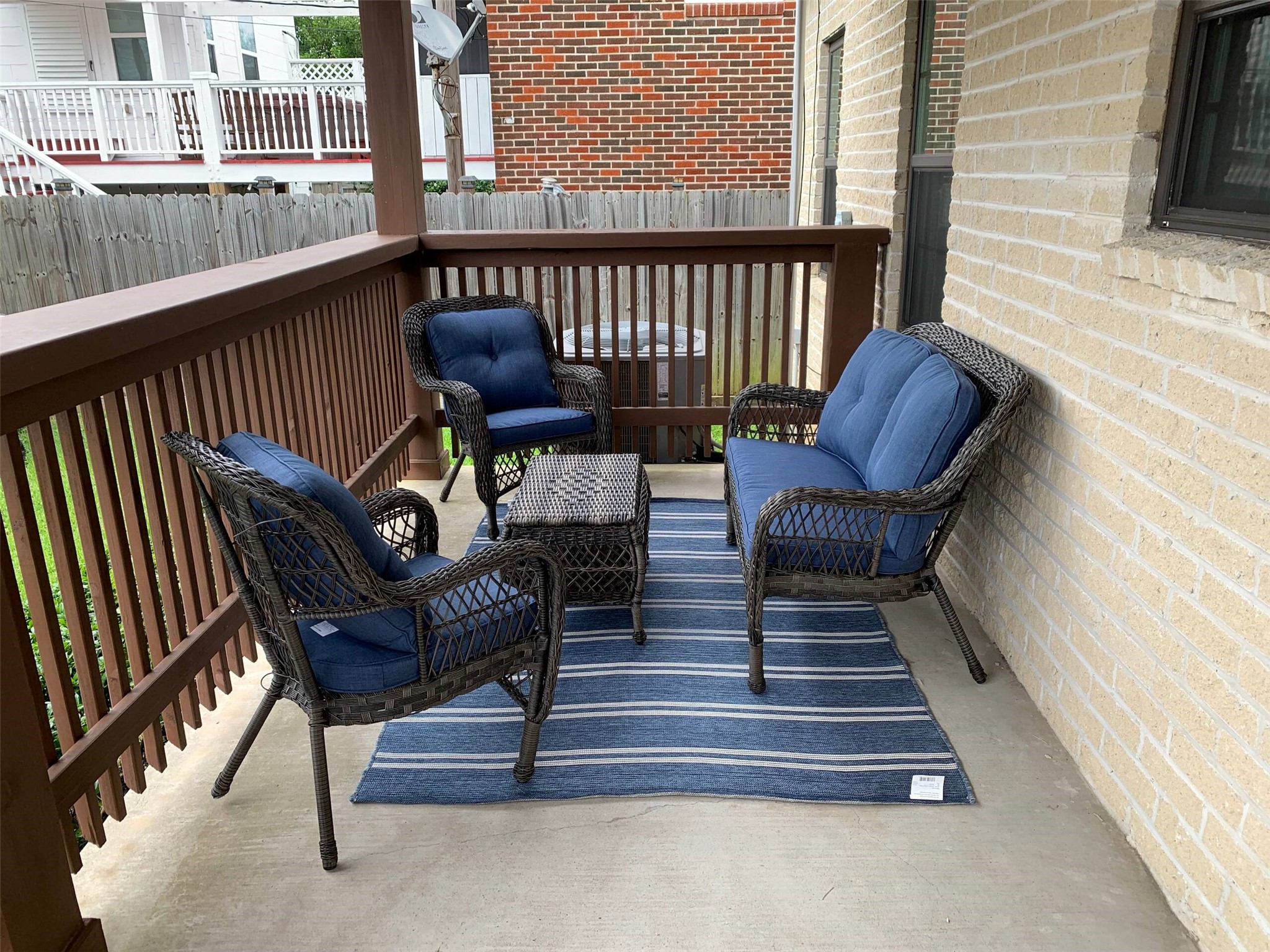 Cozy covered patio featuring stylish wicker seating with plush blue cushions, perfect for relaxing or entertaining.