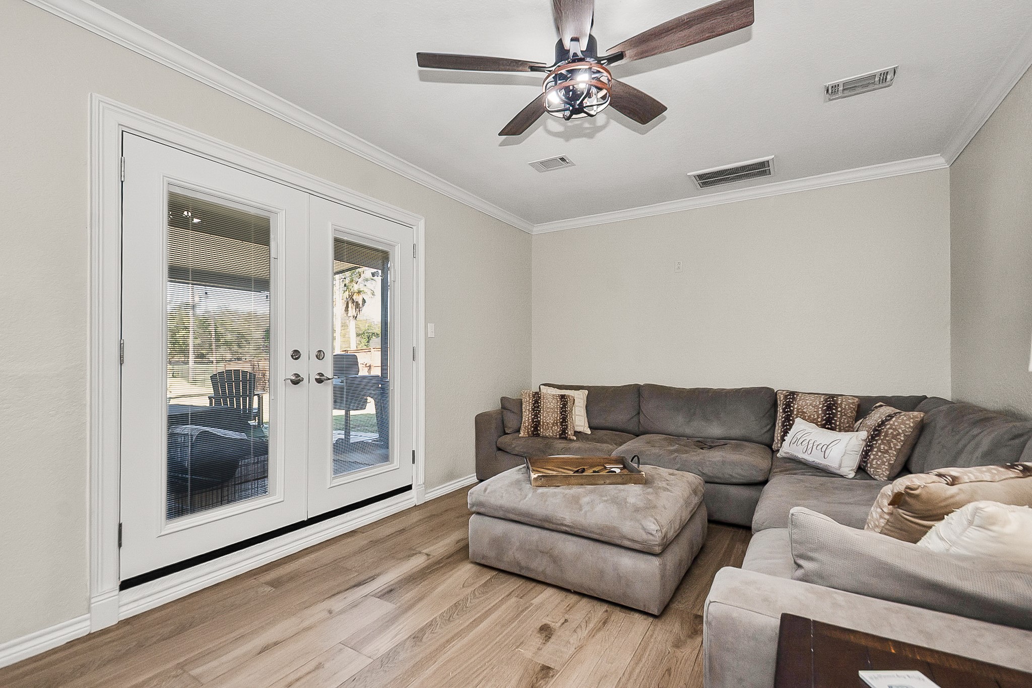 Cozy living room fits a plush size sectional sofa with stylish ceiling fan, offering a bright and inviting space with glass doors leading to an outdoor patio.