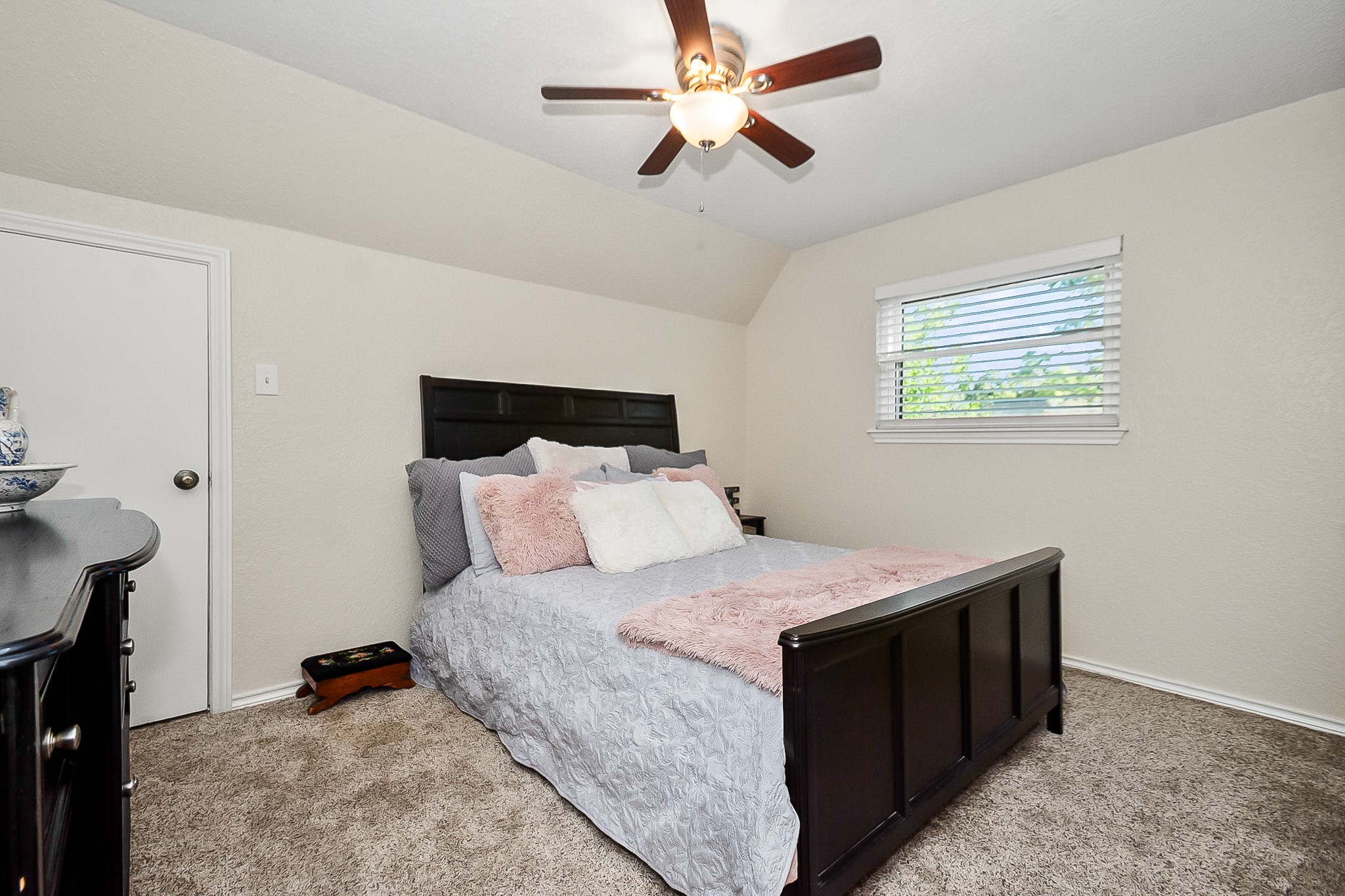 Cozy 2nd bedroom with fresh paint in neutral tones, plush carpeting, and a ceiling fan for added comfort.
