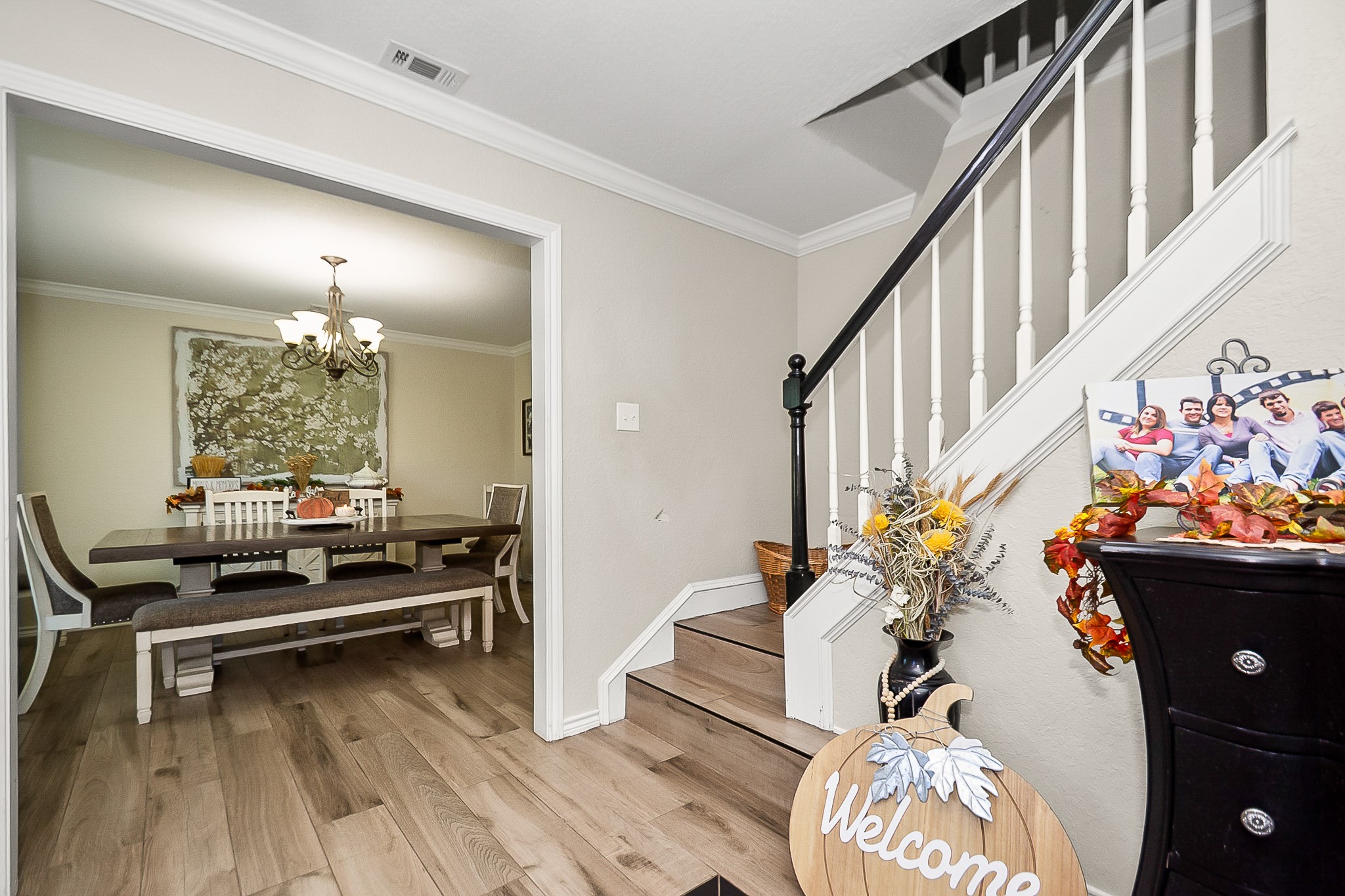 Inviting entryway with a charming staircase leads to a cozy dining area, featuring elegant lighting and fits a large wooden table perfect for gatherings.