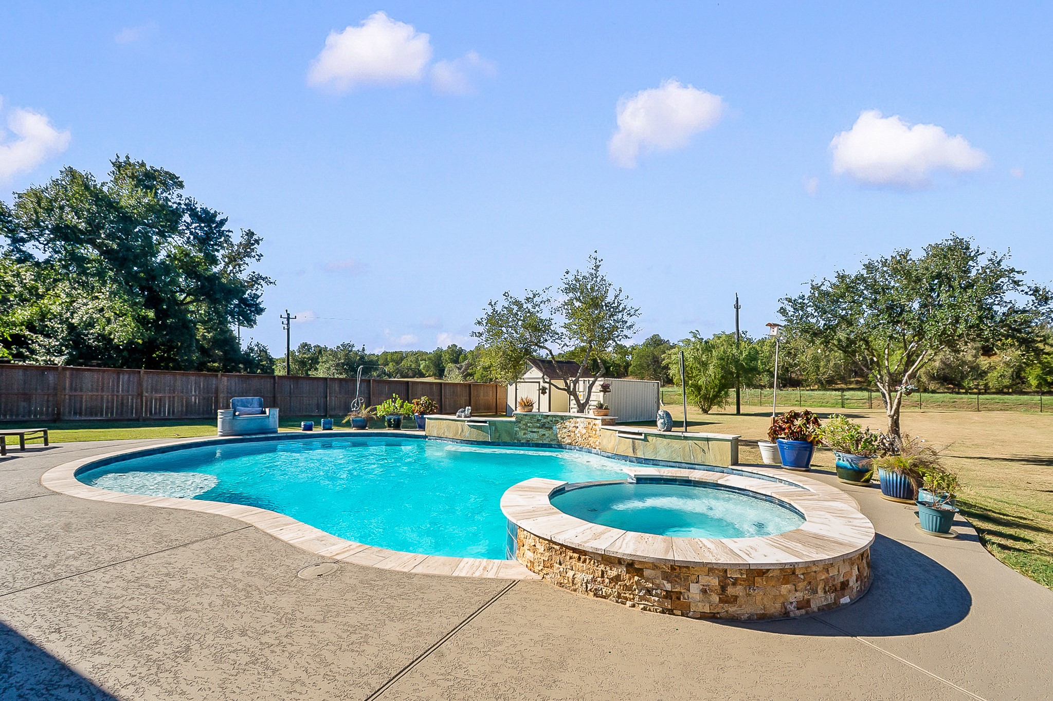 Enjoy a serene backyard oasis featuring a sparkling pool and spa, surrounded by a spacious patio and lush landscaping, perfect for relaxation and entertaining.