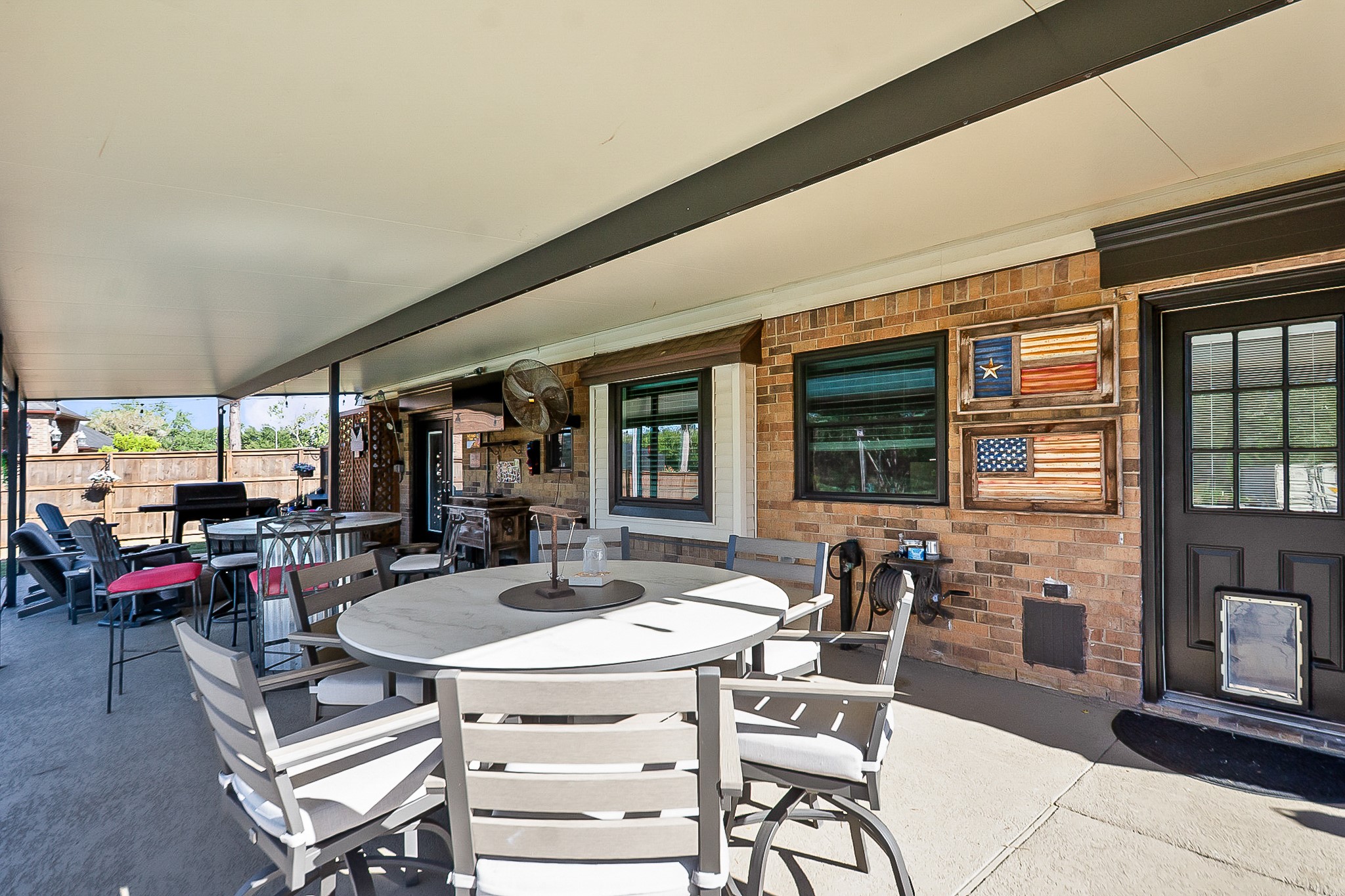 Spacious 988 sq ft covered patio perfect for outdoor entertaining, featuring a dining area, cozy seating.