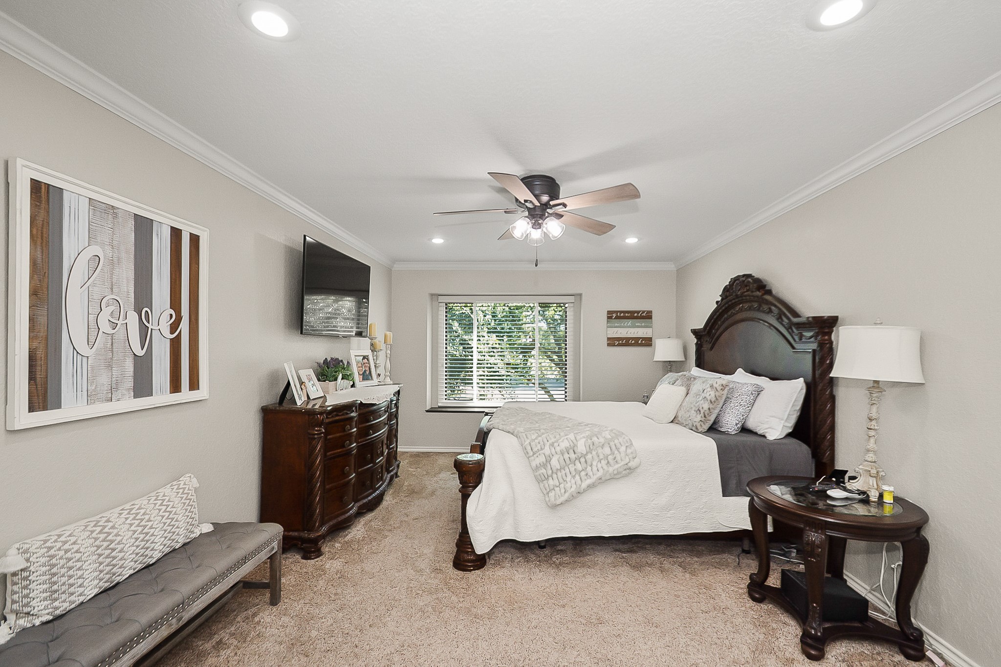 Spacious Primary bedroom with elegant furnishings, featuring a large window for natural light, plush carpeting, and a cozy seating area.