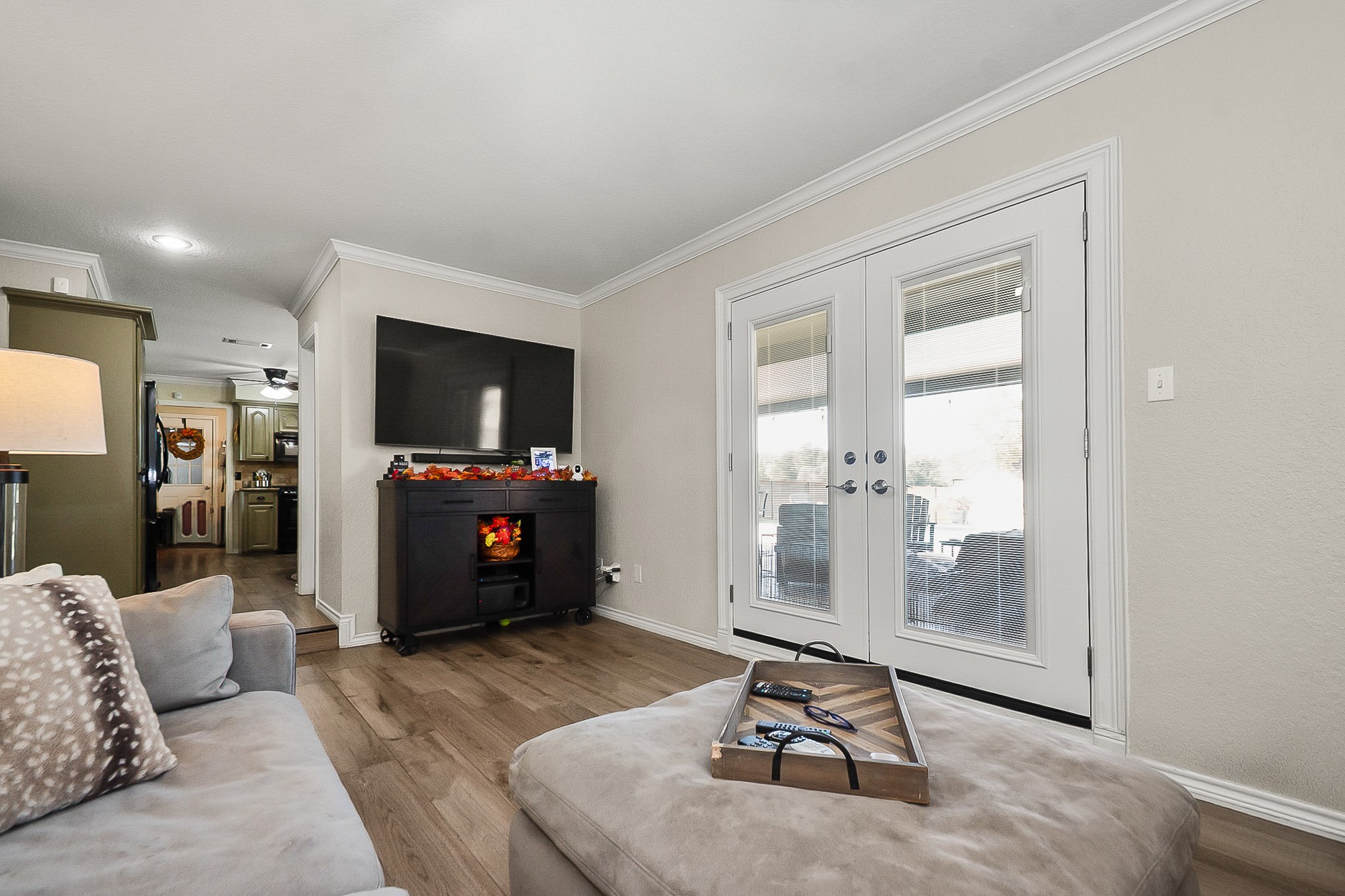 Cozy living room with elegant French doors leading to the patio, featuring a wall-mounted TV and a stylish electric fireplace for a warm ambiance.