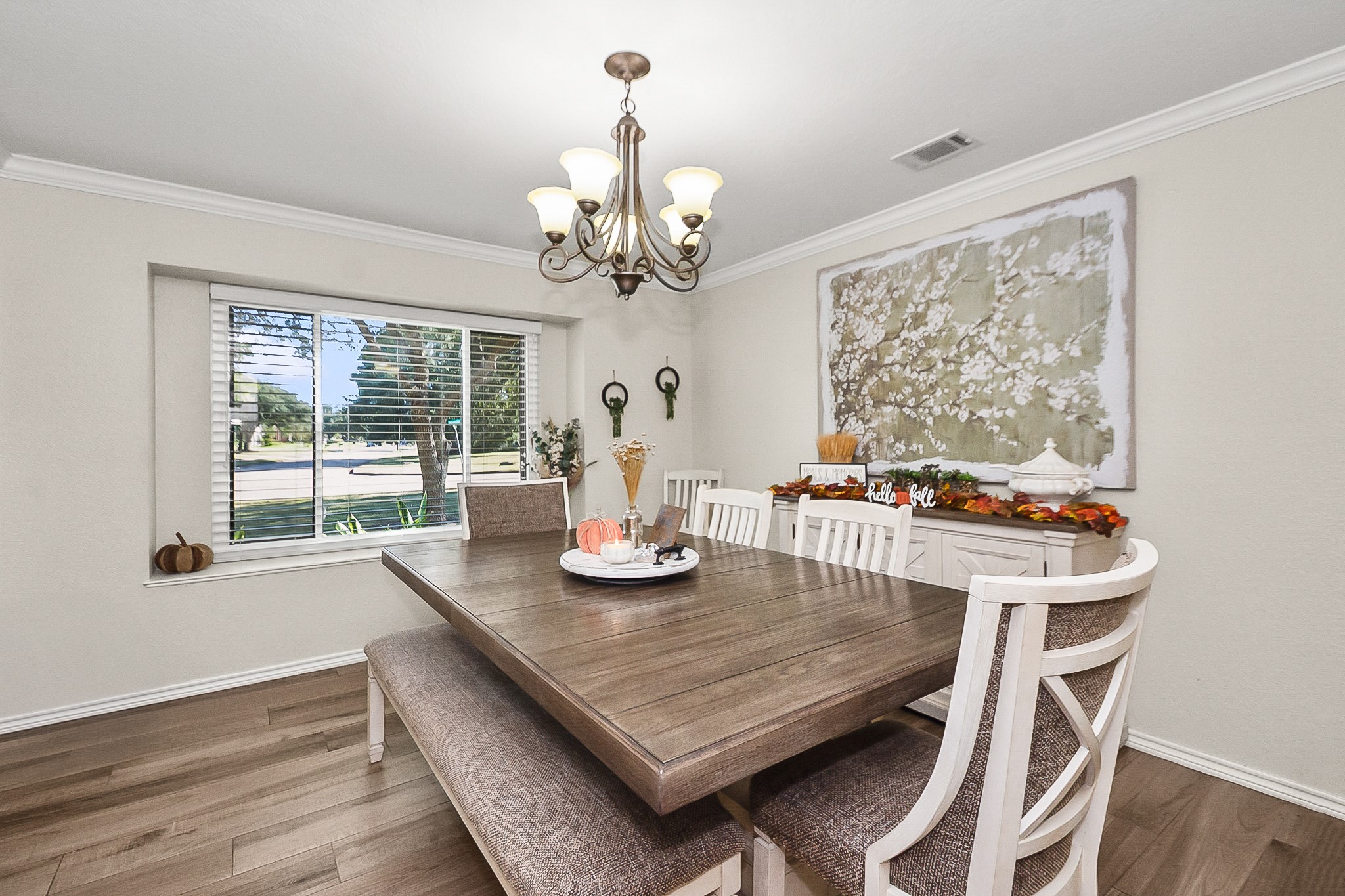 Bright and inviting dining room featuring a large window, elegant chandelier, and stylish wood look flooring, perfect for hosting gatherings.