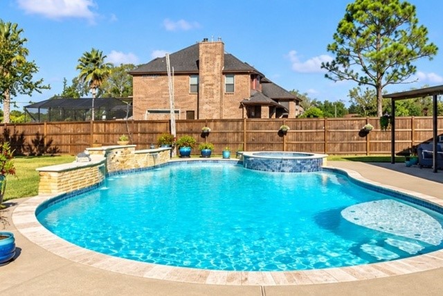 Dive into luxury with this stunning backyard oasis featuring a sparkling pool, relaxing hot tub, and elegant stone accents, perfect for entertaining and enjoying sunny days.