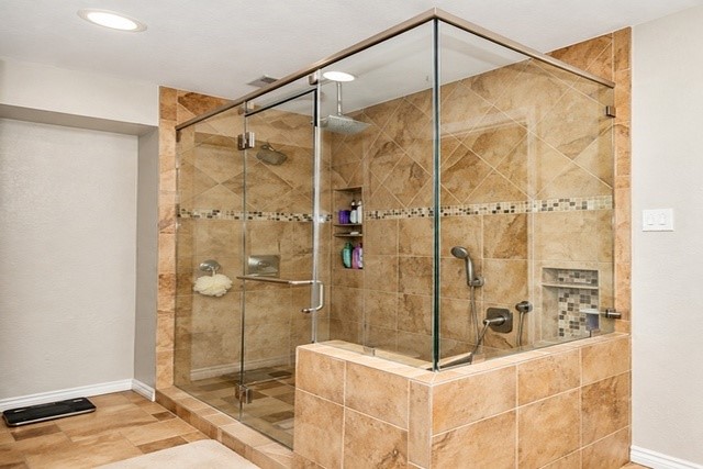 Luxurious glass-enclosed shower with elegant tilework and modern fixtures, offering a spacious and stylish bathing experience.