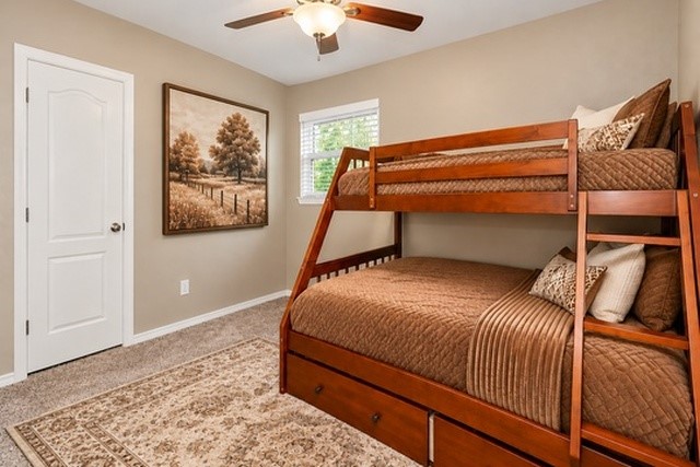 Cozy 4th bedroom featuring a wooden bunk bed with storage, warm brown tones, and a stylish ceiling fan, creating an inviting retreat.
