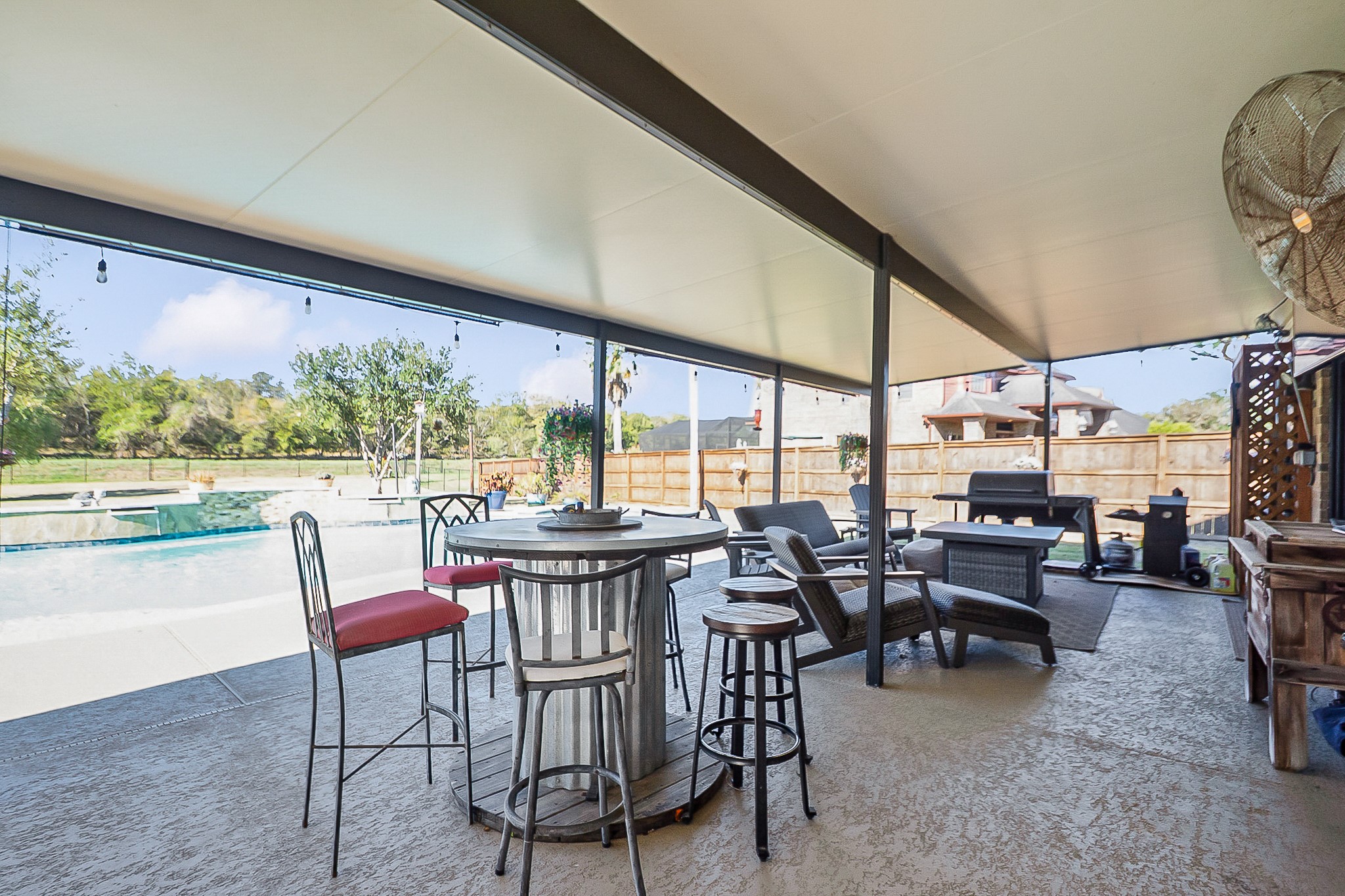 Spacious 988 sq. ft. Covered patio with seating and dining area overlooks a sparkling pool, perfect for outdoor entertaining.