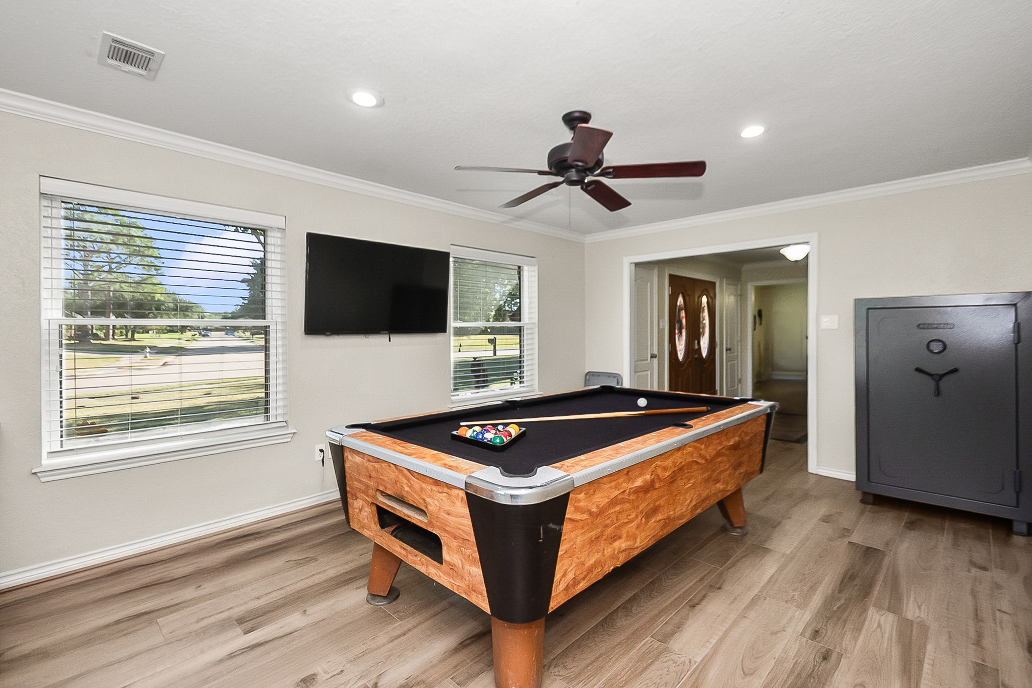 Spacious game room featuring a stylish pool table, sleek wood look floors, and ample natural light, perfect for entertainment and relaxation. can also be used as a formal Living room or you decide.