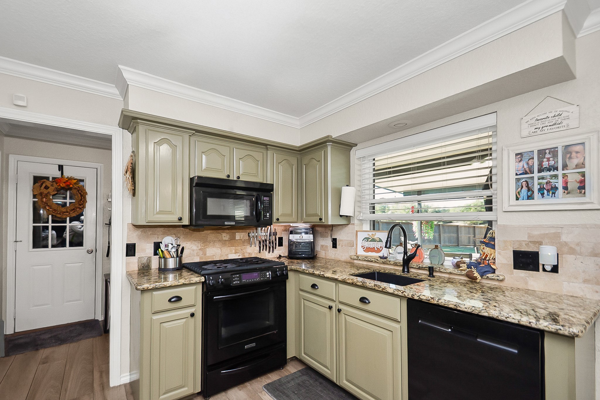 Charming kitchen with sage green cabinets, granite countertops, and a cozy window view, featuring modern appliances and a convenient layout.