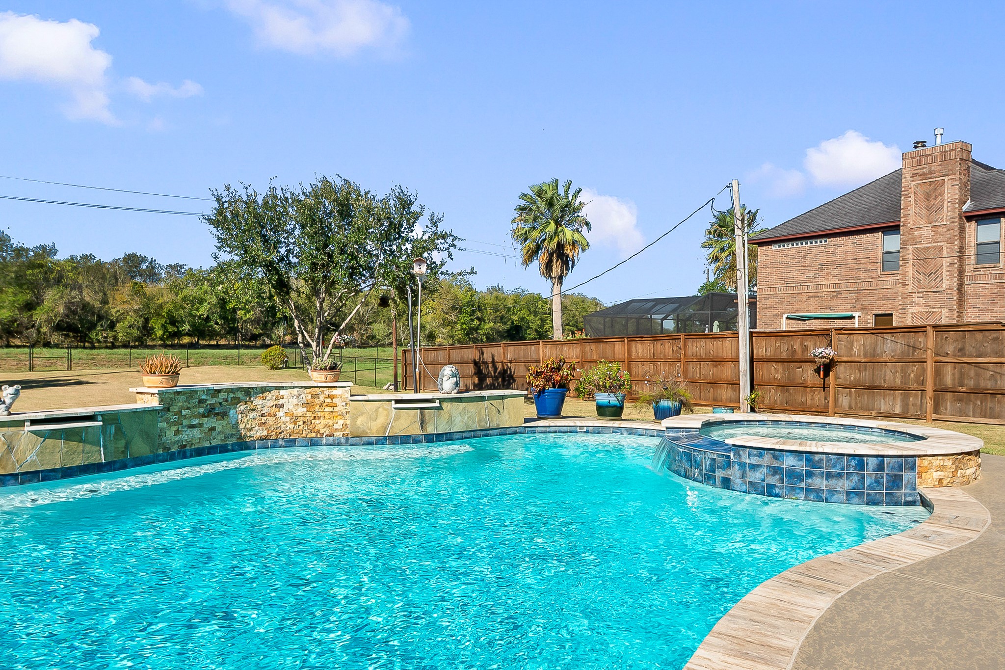 Stunning backyard oasis featuring a sparkling heated pool and spa, surrounded by lush landscaping and a privacy fence, perfect for relaxation and entertaining.