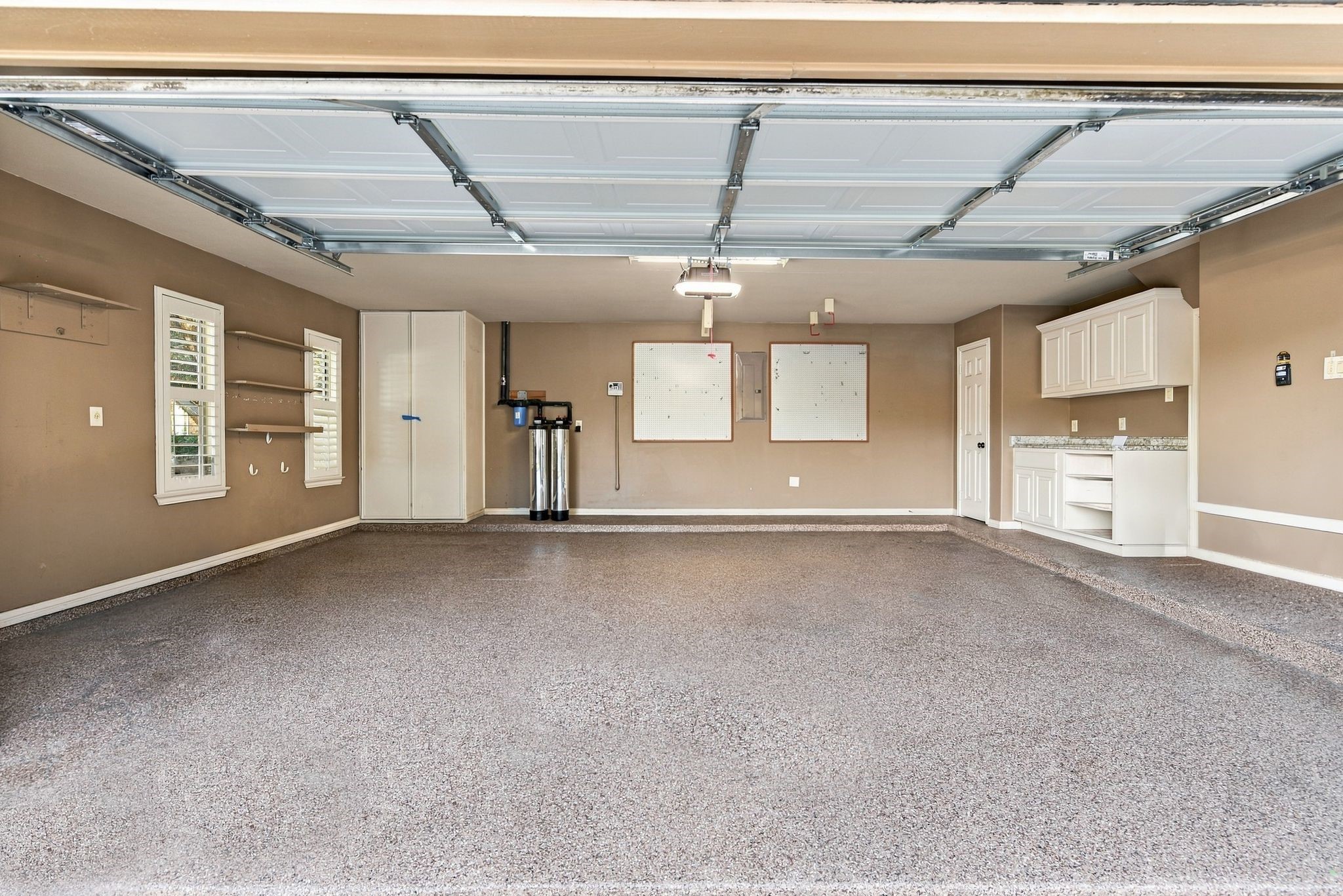 Oversized two-car garage with epoxy flooring, built-in storage cabinets, and a workbench area, perfect for organization and projects.