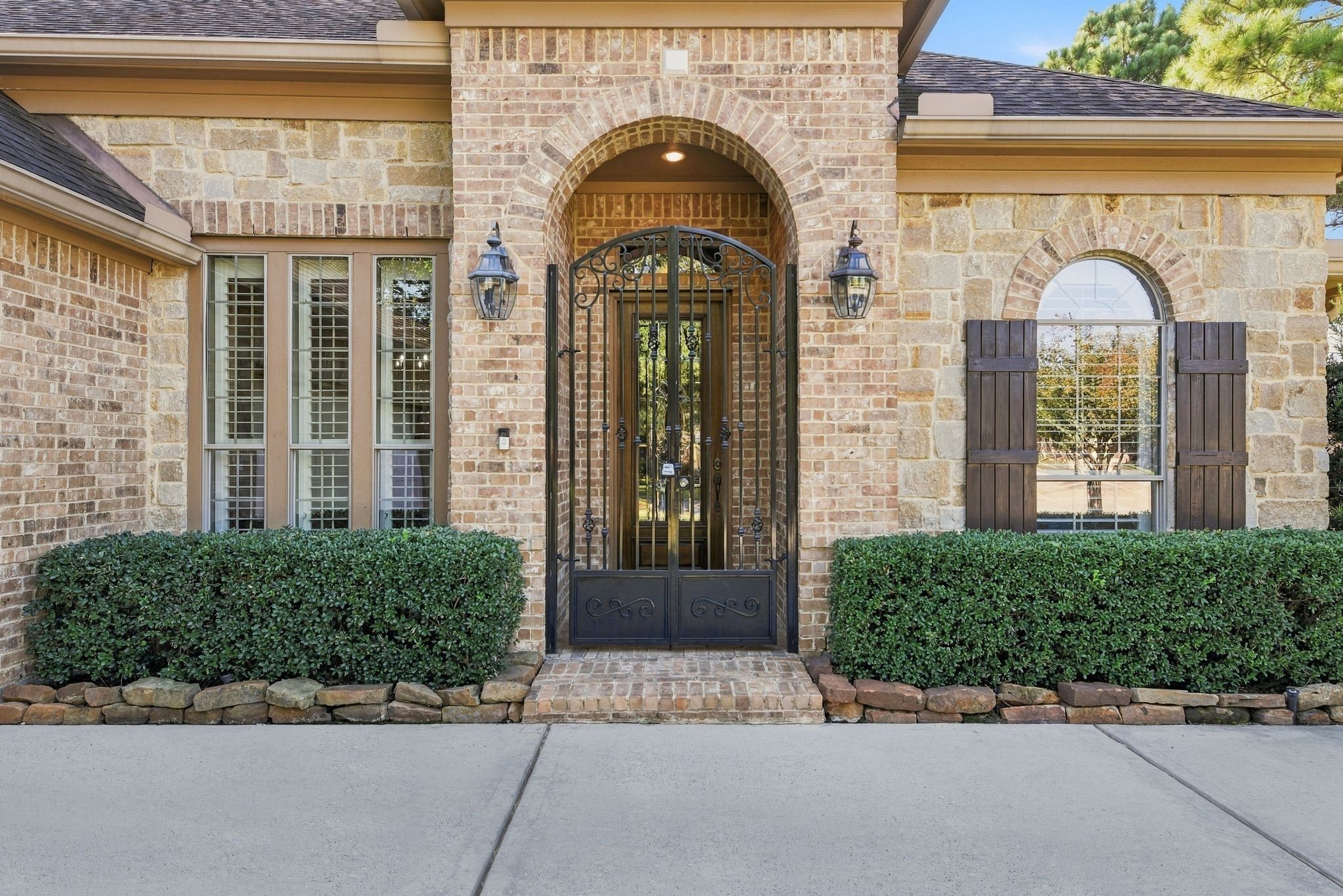 Gorgeous brick and stone exterior with elegant arched entryway and decorative wrought iron gate entry. Gorgeous brick and stone exterior with elegant arched entryway and decorative wrought iron gate entry.