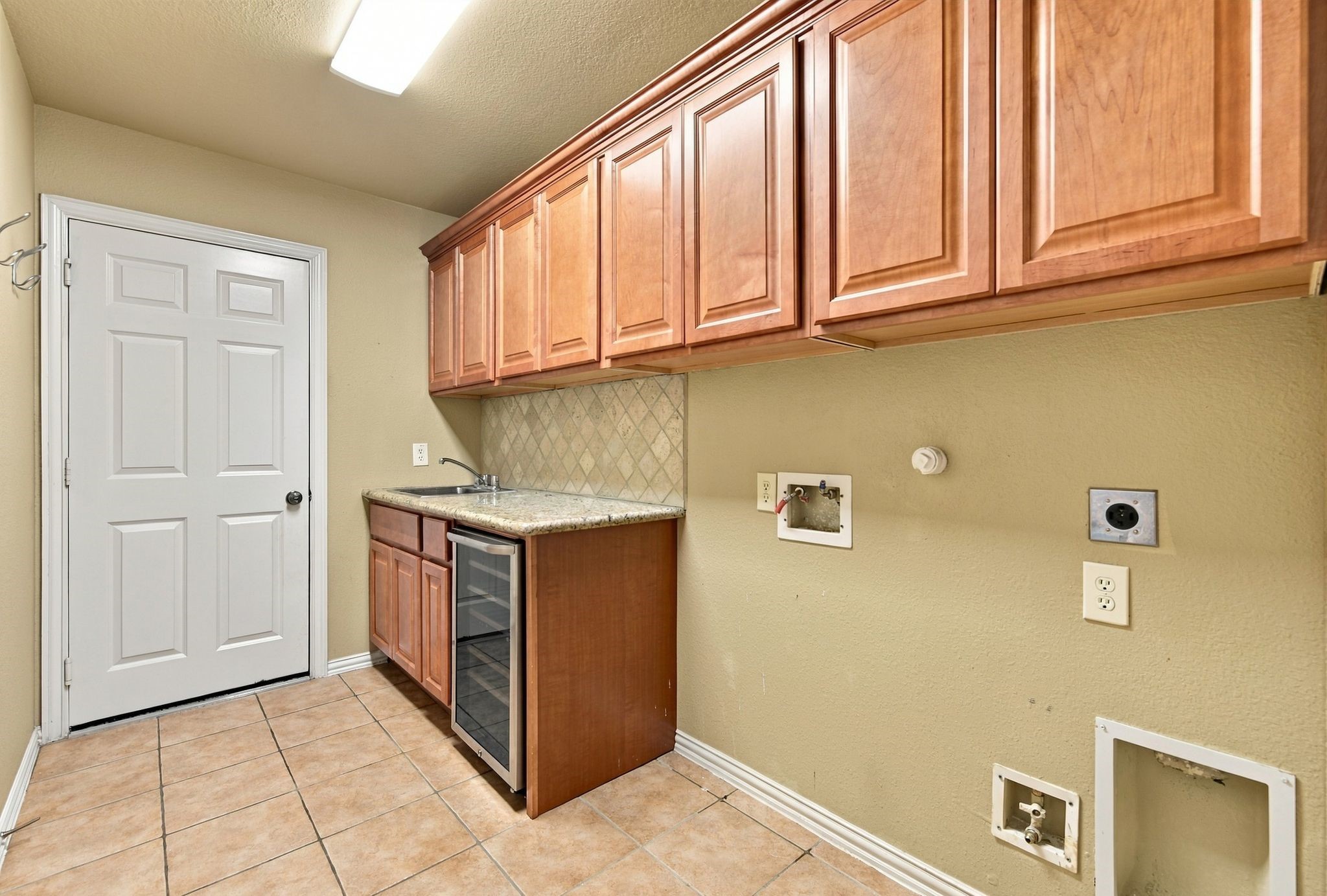 Large utility room featuring cabinetry, a convenient sink, and wine fridge.