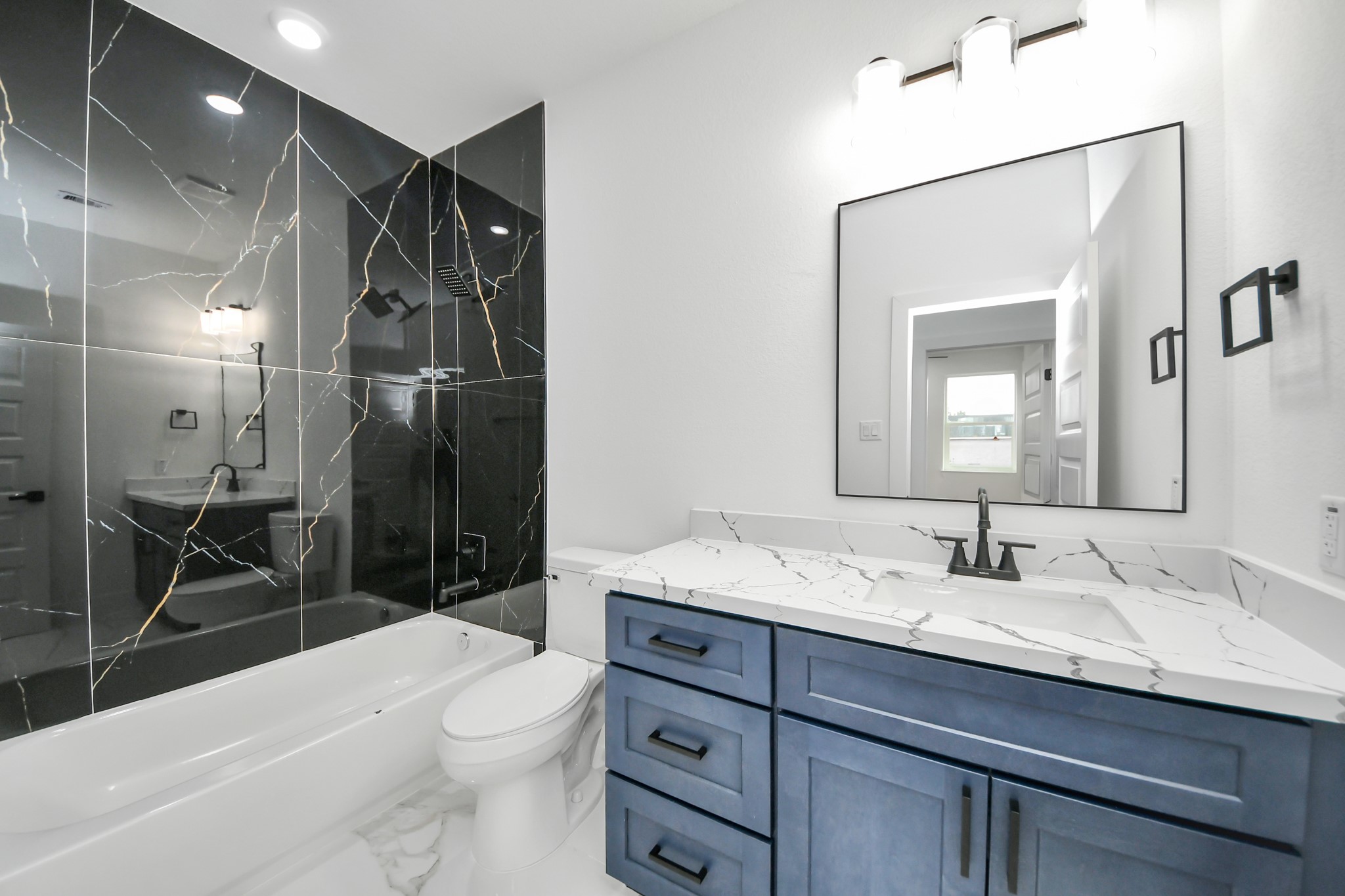 Elegant bathroom featuring a luxurious black marble shower wall, sleek vanity with a marble countertop, and modern fixtures for a sophisticated touch.