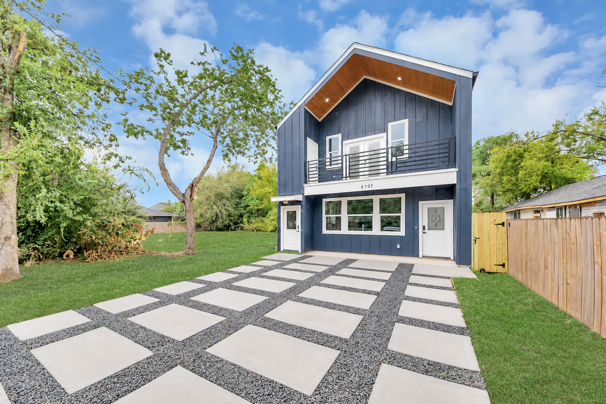 Modern two-story home with striking blue exterior, large windows, and a sleek balcony. The spacious driveway features a stylish geometric design, and the lush lawn provides ample outdoor space. Modern two-story home with striking blue exterior, large windows, and a sleek balcony. The spacious driveway features a stylish geometric design, and the lush lawn provides ample outdoor space.