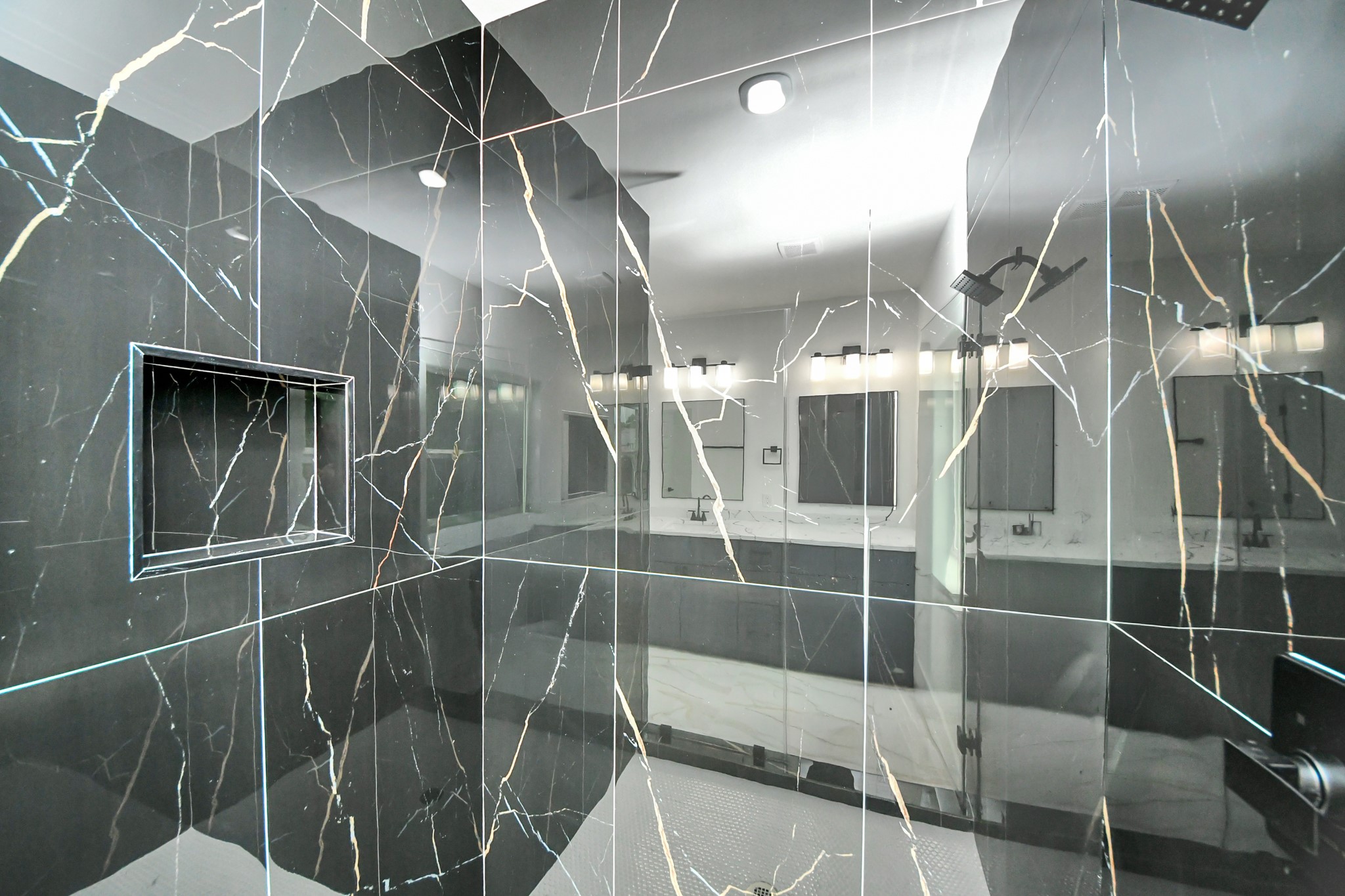 Luxurious bathroom featuring a sleek, black marble shower with elegant veining and a built-in niche for convenience.