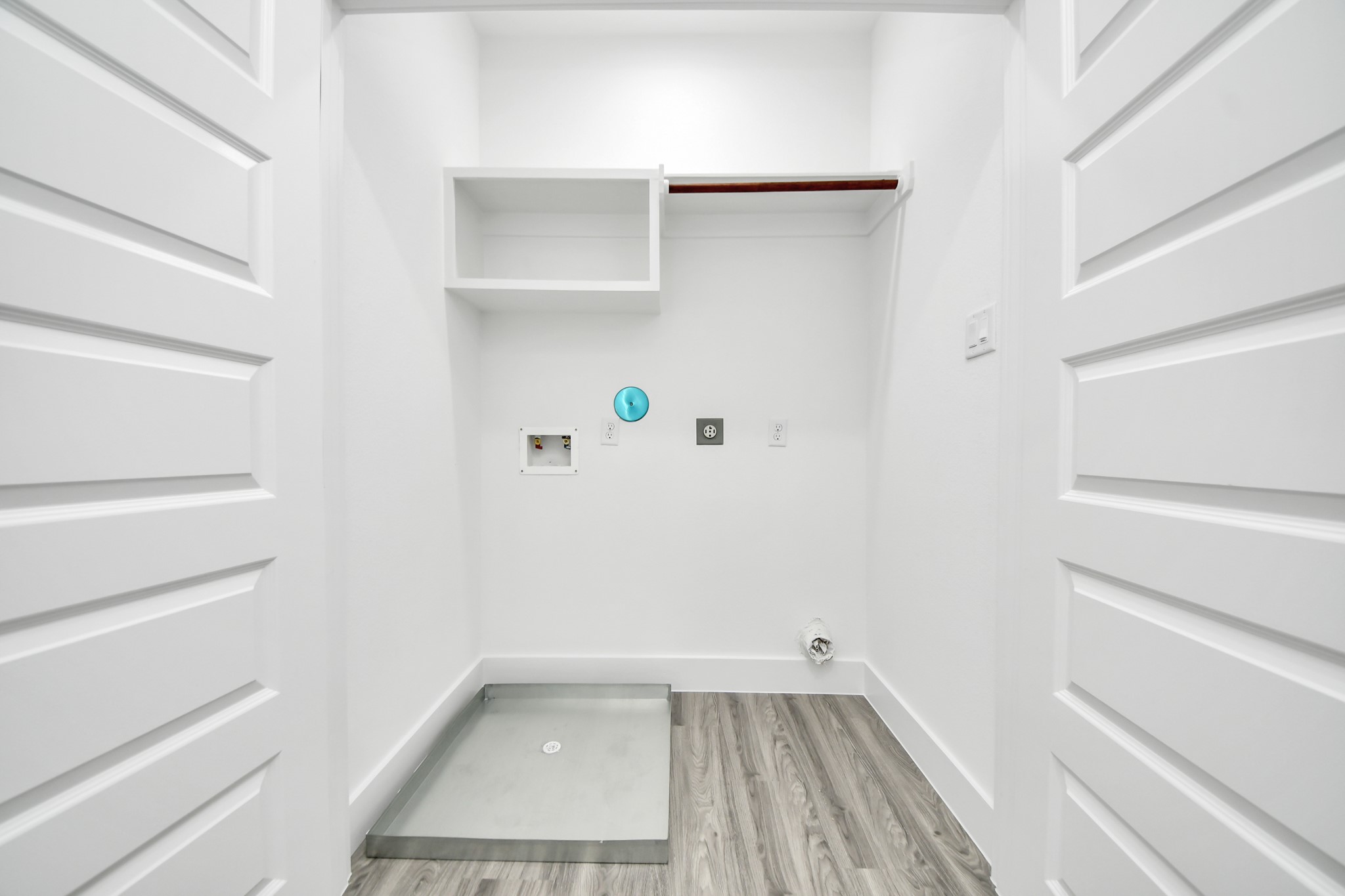 Bright and functional laundry room featuring hookups for appliances, a convenient shelf for storage, and modern laminate flooring.