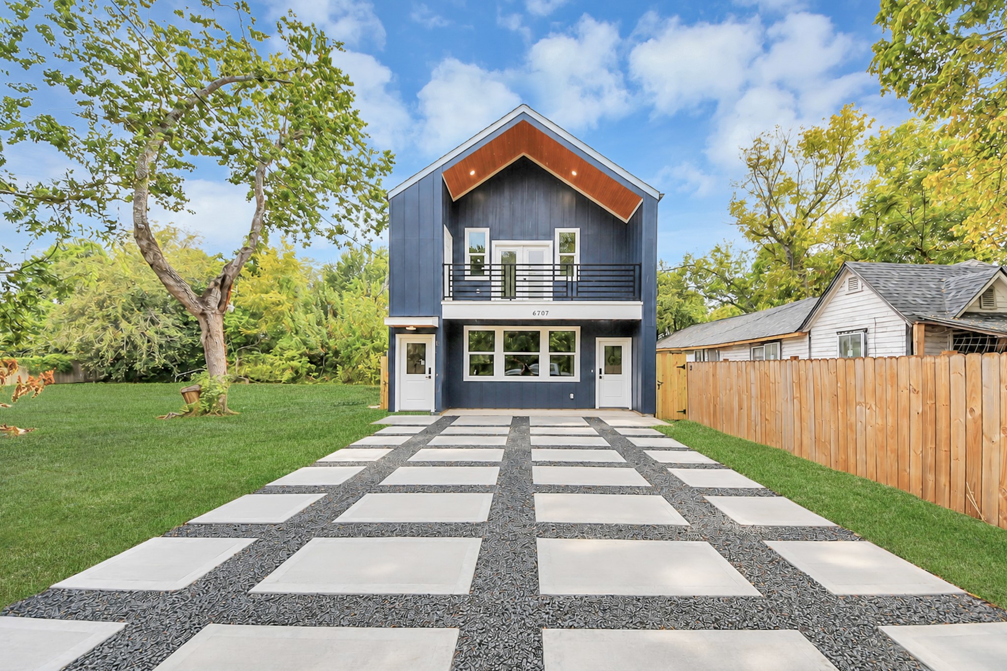 Modern two-story home with a striking facade, spacious balcony, and sleek geometric driveway, set amidst lush greenery for a serene living experience. Modern two-story home with a striking facade, spacious balcony, and sleek geometric driveway, set amidst lush greenery for a serene living experience.