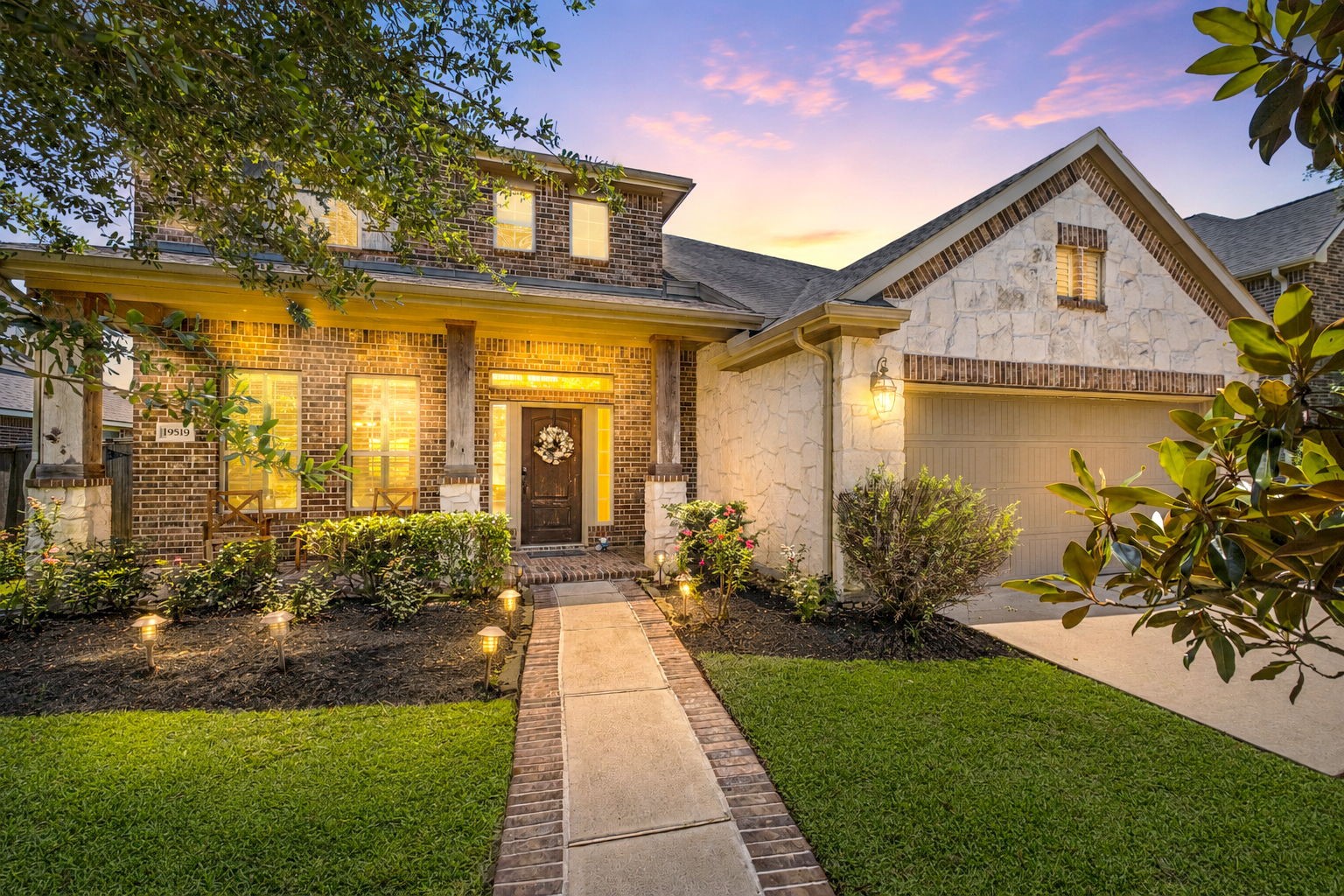 This inviting home features a charming brick and stone exterior. A welcoming front porch, mature landscaping, and two-car garage enhance its curb appeal.